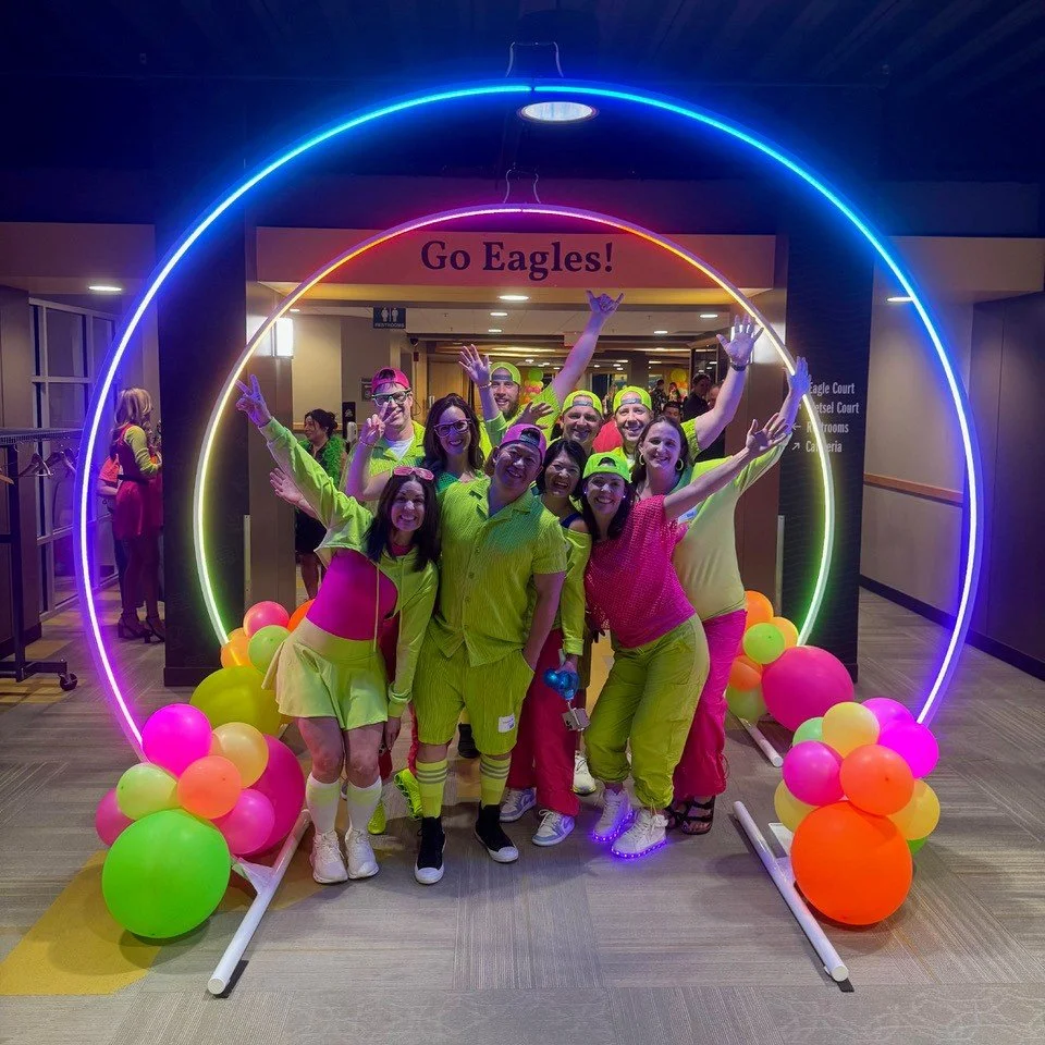 group dressed in neon clothing under glowing neon orbs at auction event