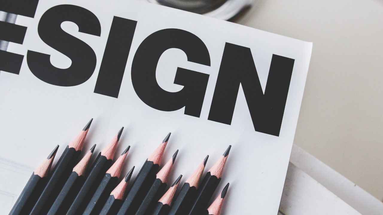 Nahaufnahme von mehreren schwarzen Buntstiften auf einem weißen Papier mit großen schwarzen Buchstaben. | mls lume