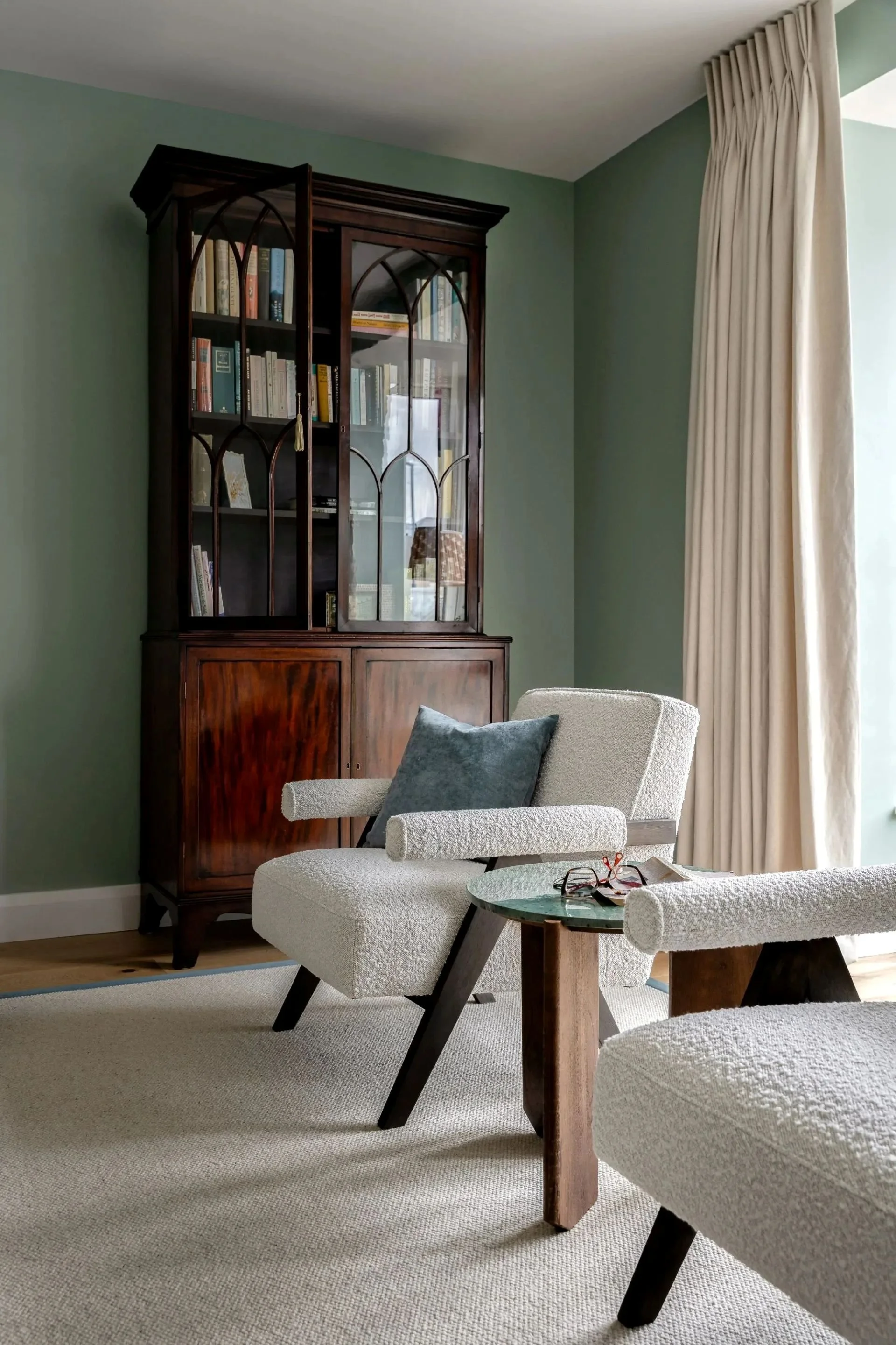 Comforting and elegant Kilkenny sitting room with antique Georgian bookcase and boucle chairs.