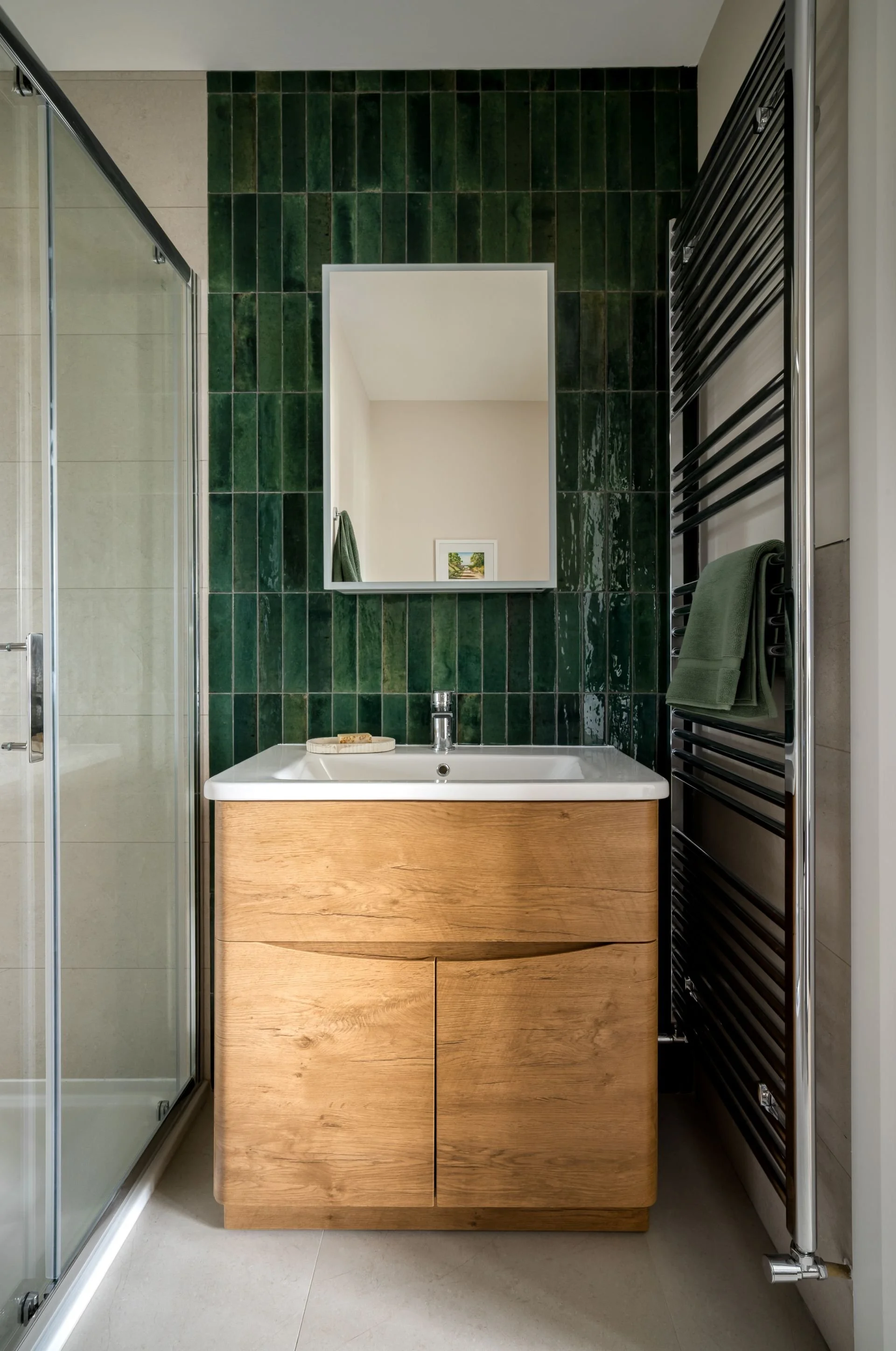 Modern Irish bathroom with green tiles and wood vanity.