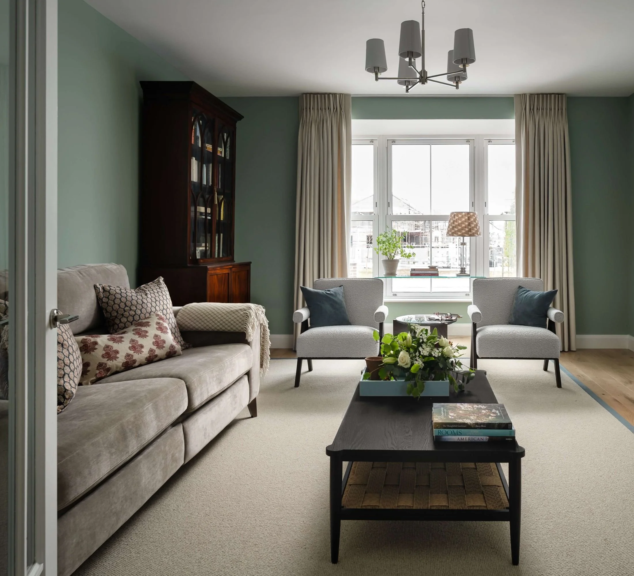 Sitting room designed by South Hill Studio in Kilkenny, featuring soft green walls, tailored curtains, antique furniture and a calm, collected seating area.