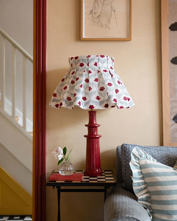 Fabric lampshade on a red ceramic lampbase in a countryside sitting room in Ireland.