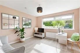 Pale pink home office and playroom with large window and green accents