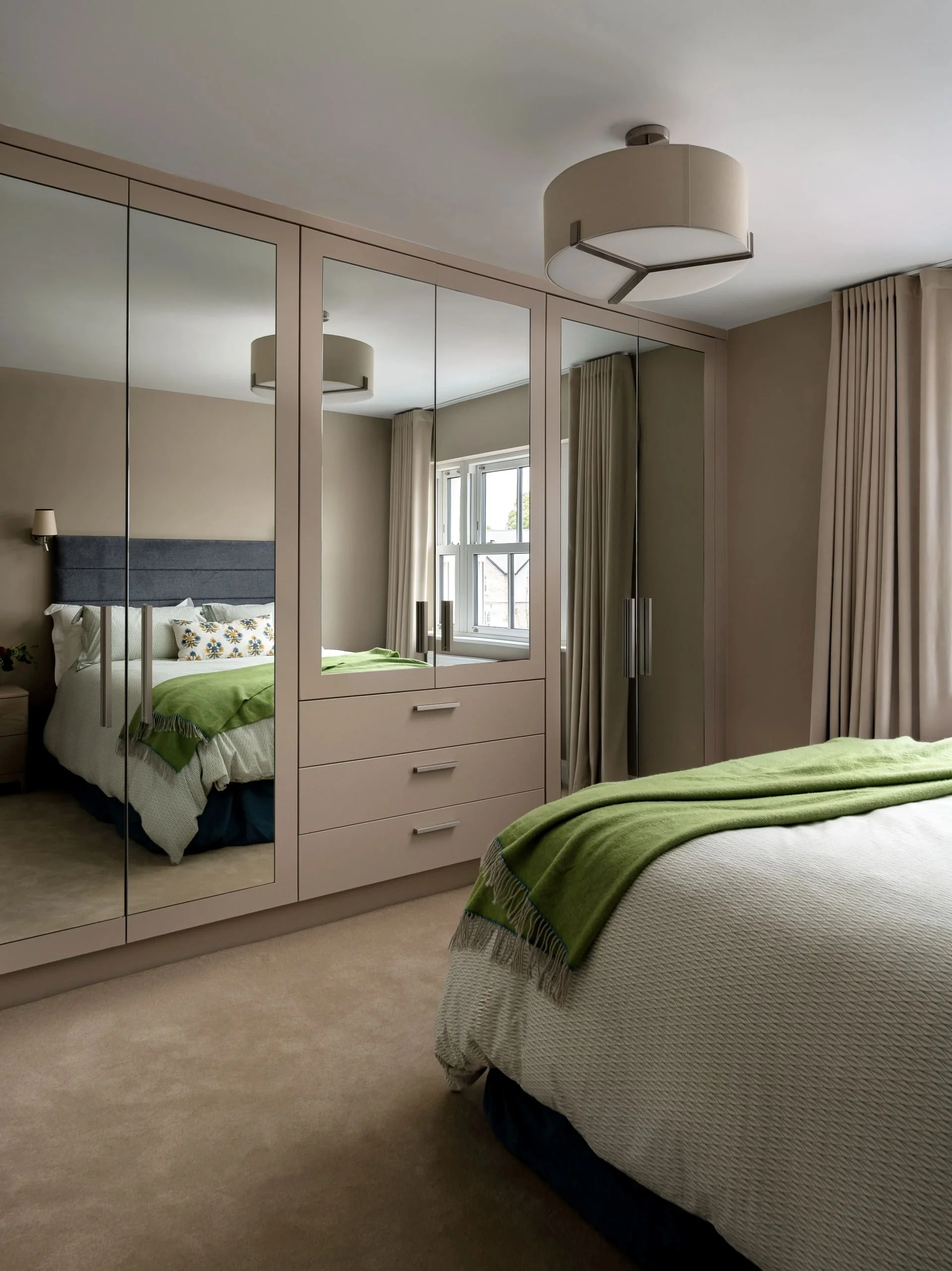 Bespoke mirrored wardrobes in primary bedroom decorated in warm tones.