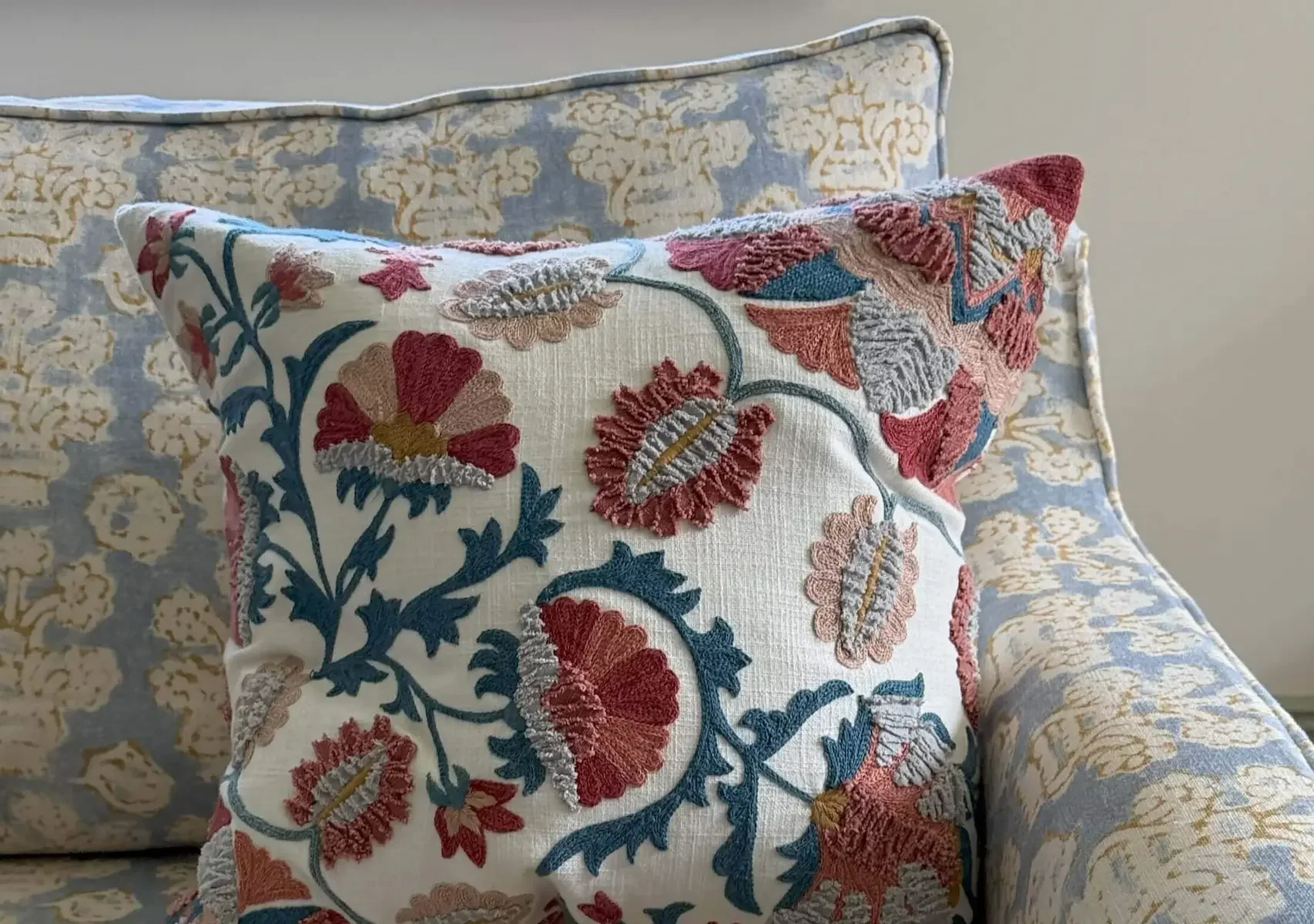 Custom Linwood upholstered sofa with embroidered blue and rust red cushion