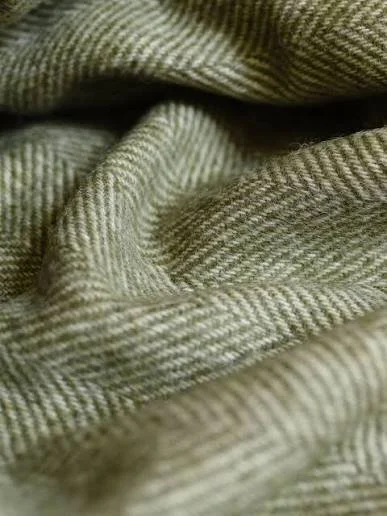 Close-up of olive green herringbone wool throw with texture and folds.