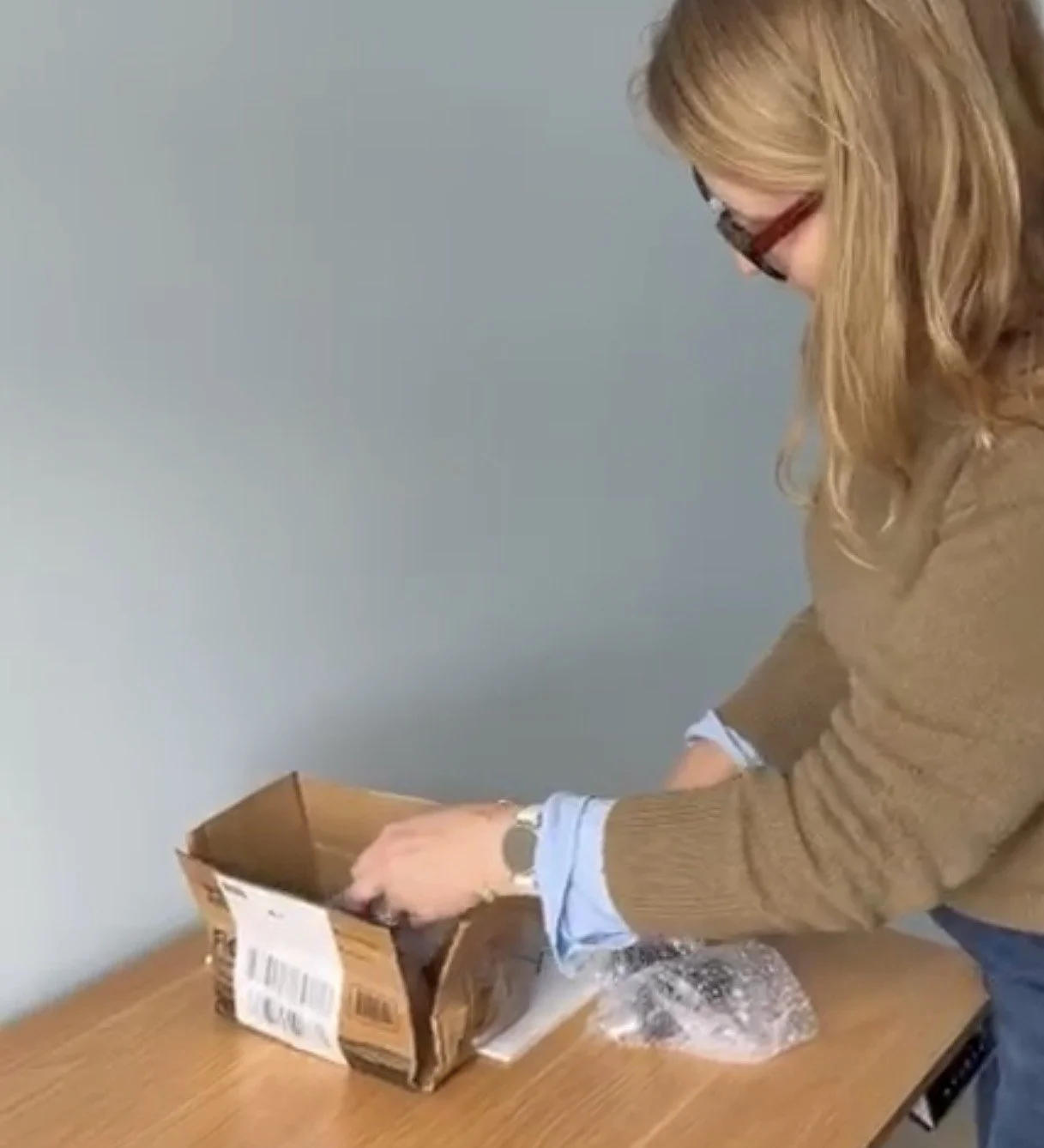 Interior Designer Liz Druhan, of South Hill Studio, opening custom brass hardware on a wooden table.