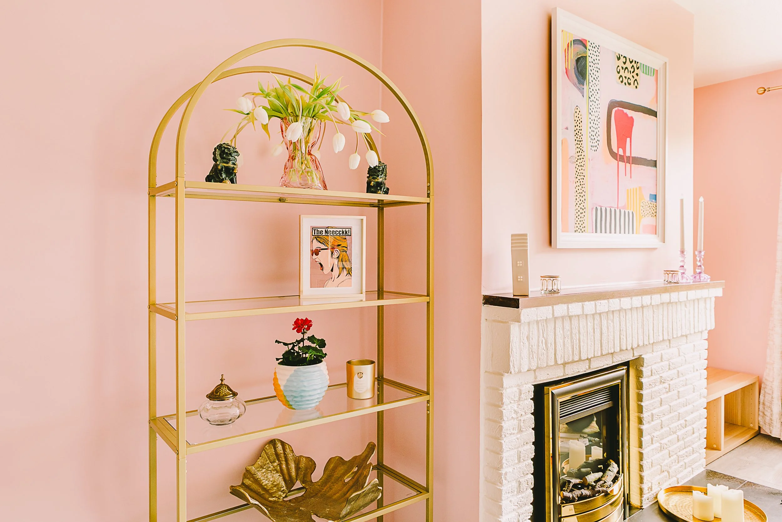 Pink sitting room with polished brass electric fire and shelving