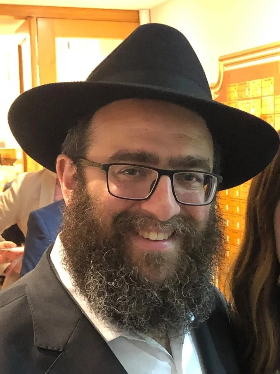 A smiling woman with glasses and earrings in a casual indoor setting.
