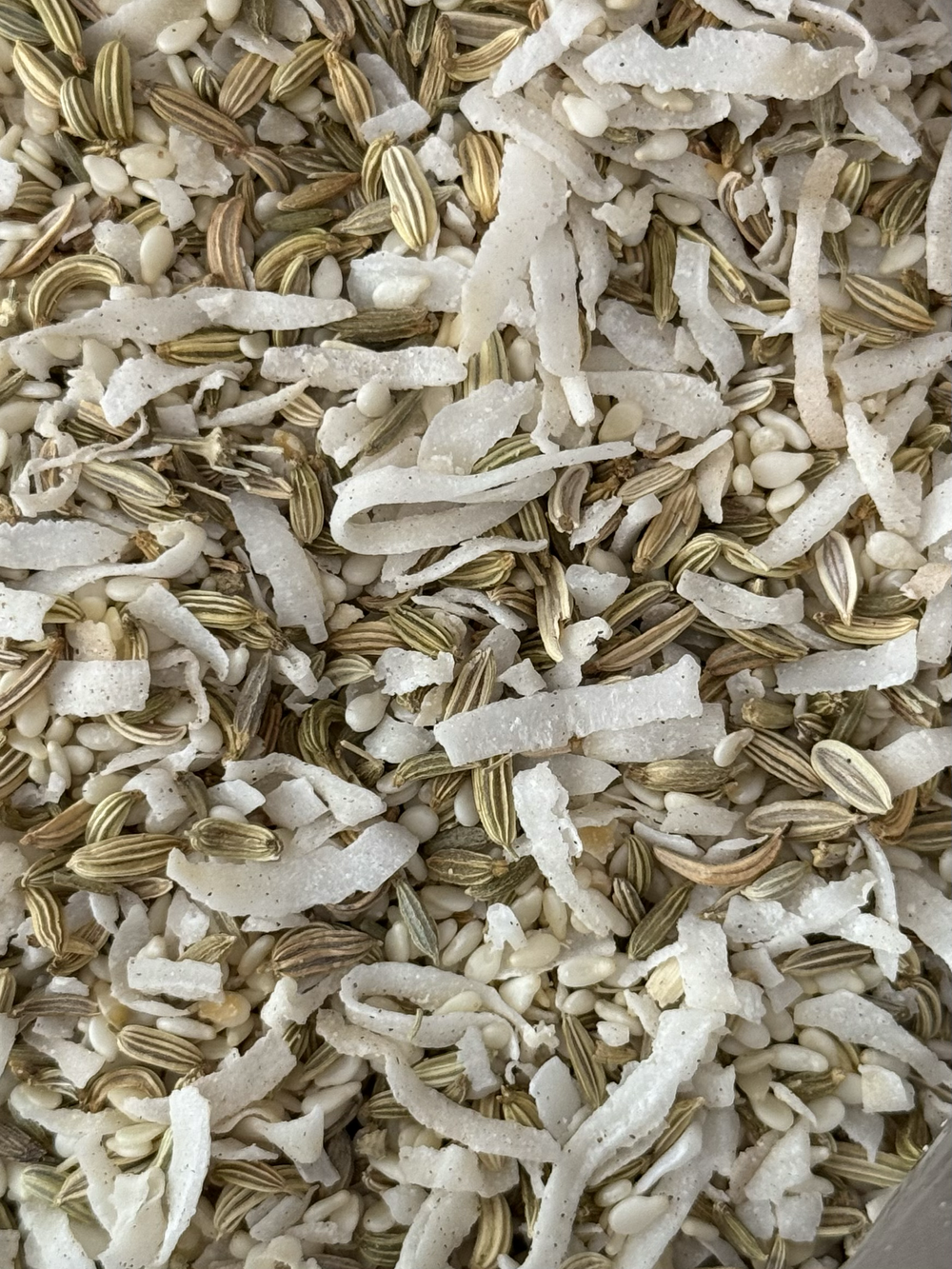 Close-up of a mixture of sunflower seed shells, small white seeds, and shredded nut or seed pieces.