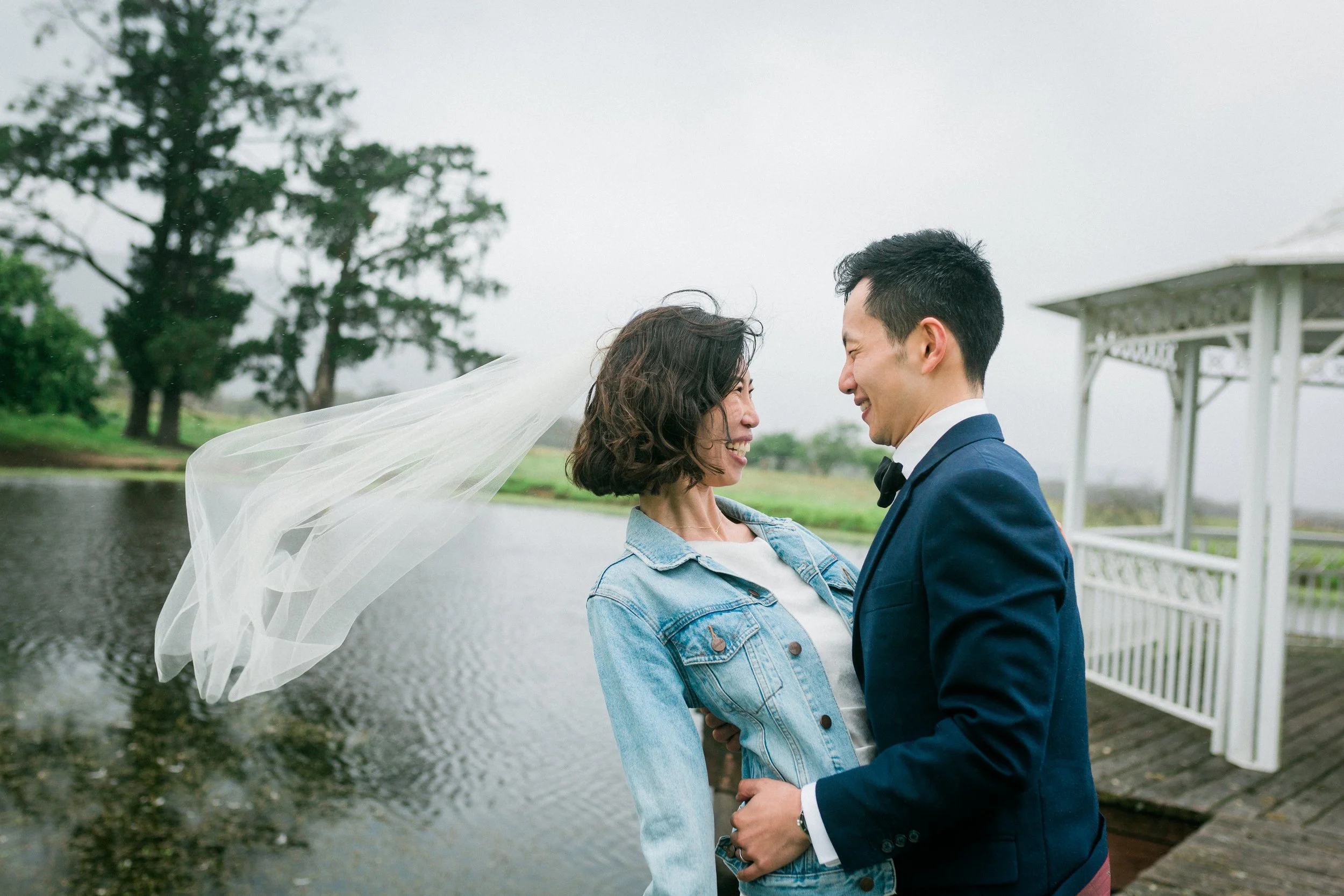 A couple shares a quiet moment beside a pond and white gazebo during their Blue Mountains elopement — relaxed, romantic, and full of joy.