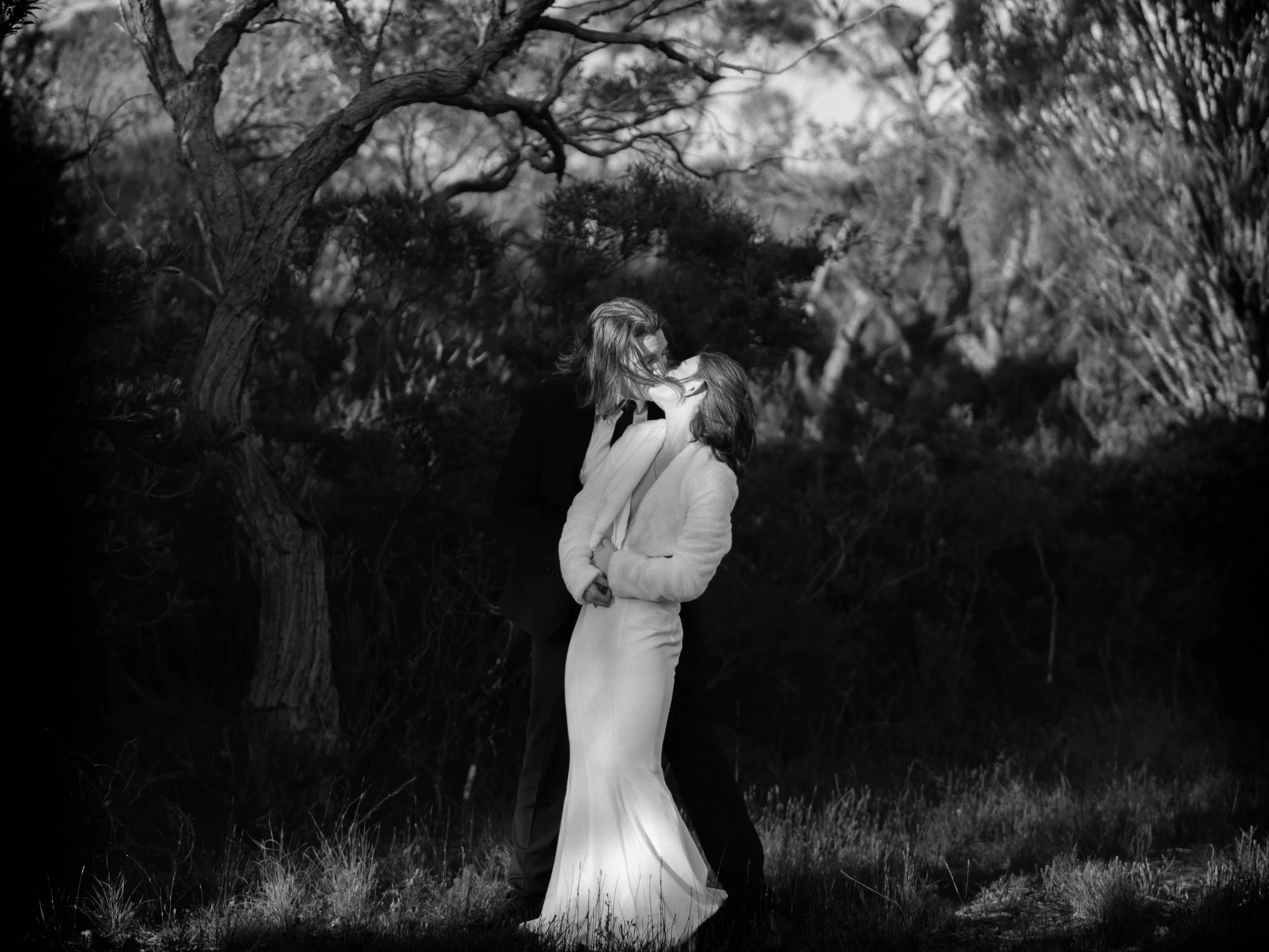 A timeless black-and-white photo of a couple sharing a kiss amid tall grass — a classic moment from a Blue Mountains elopement.