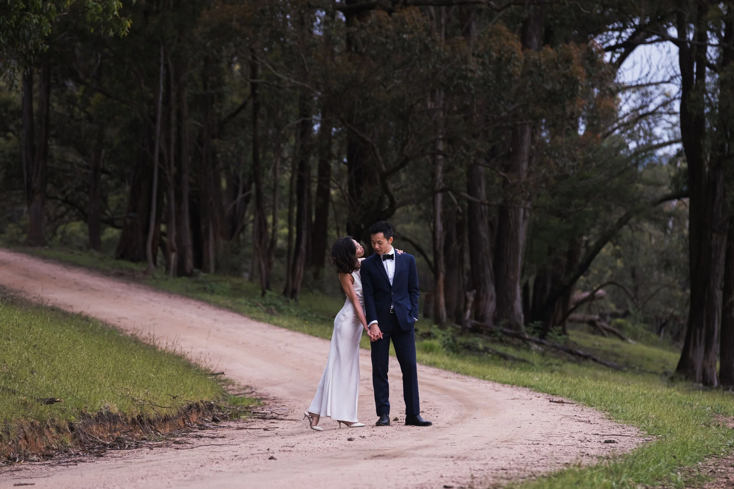 An eloping couple walks hand in hand through a forest path in the Blue Mountains, surrounded by natural beauty and calm simplicity.