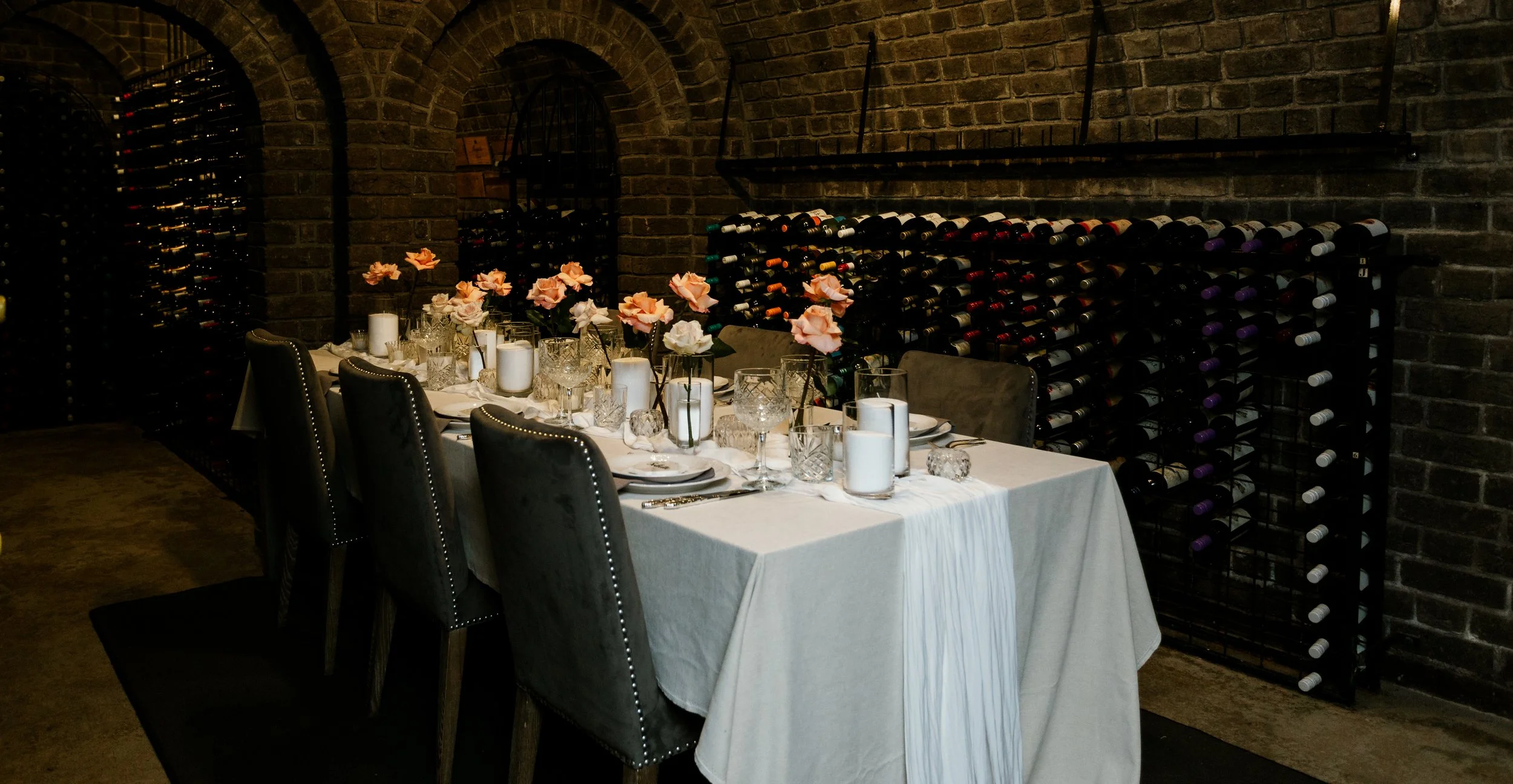 An intimate dinner table set with candles and flowers inside a cozy wine cellar — a romantic setting for a Blue Mountains elopement celebration.