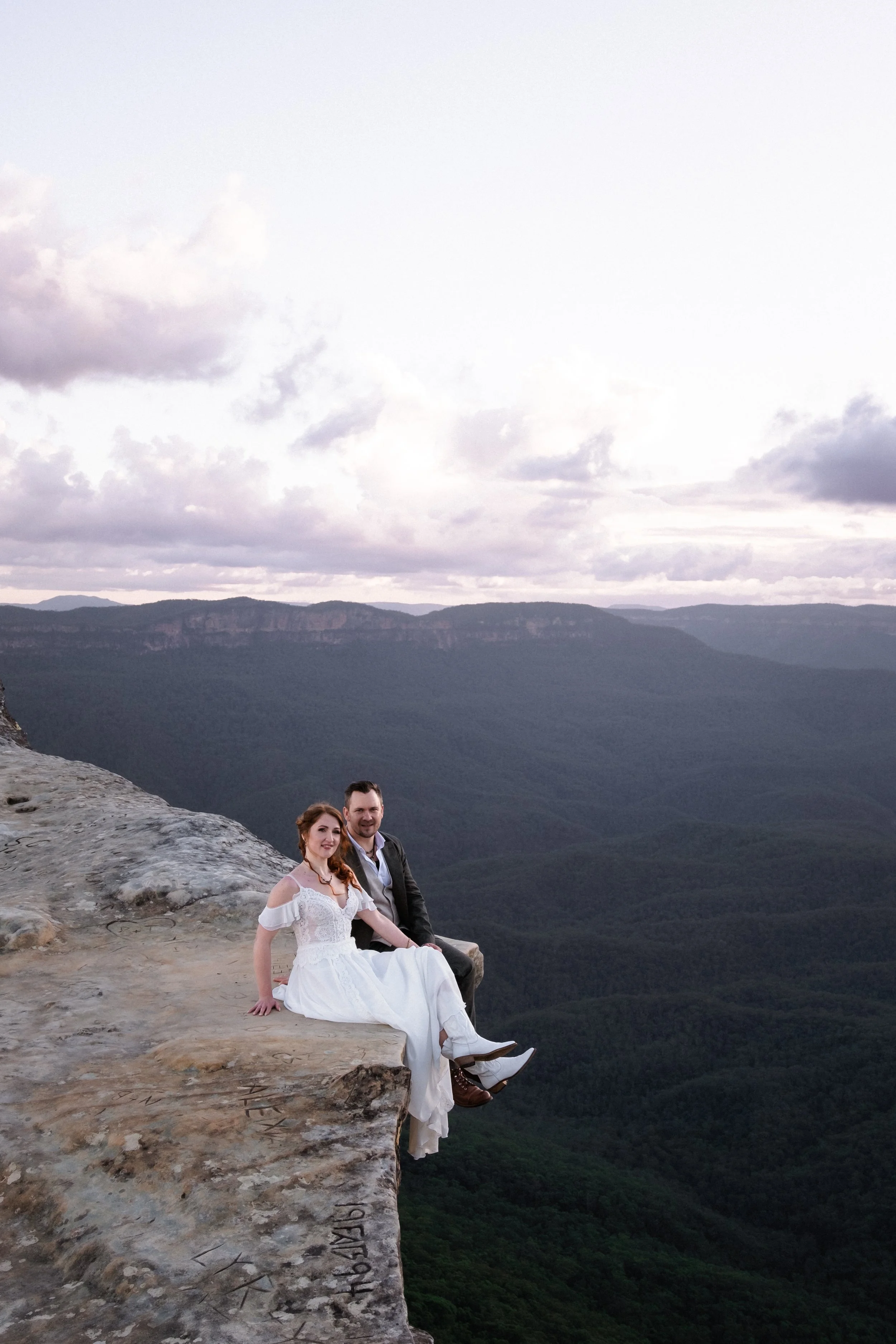 An eloping couple shares a kiss on a country path surrounded by greenery — simple, romantic, and beautifully intimate.
