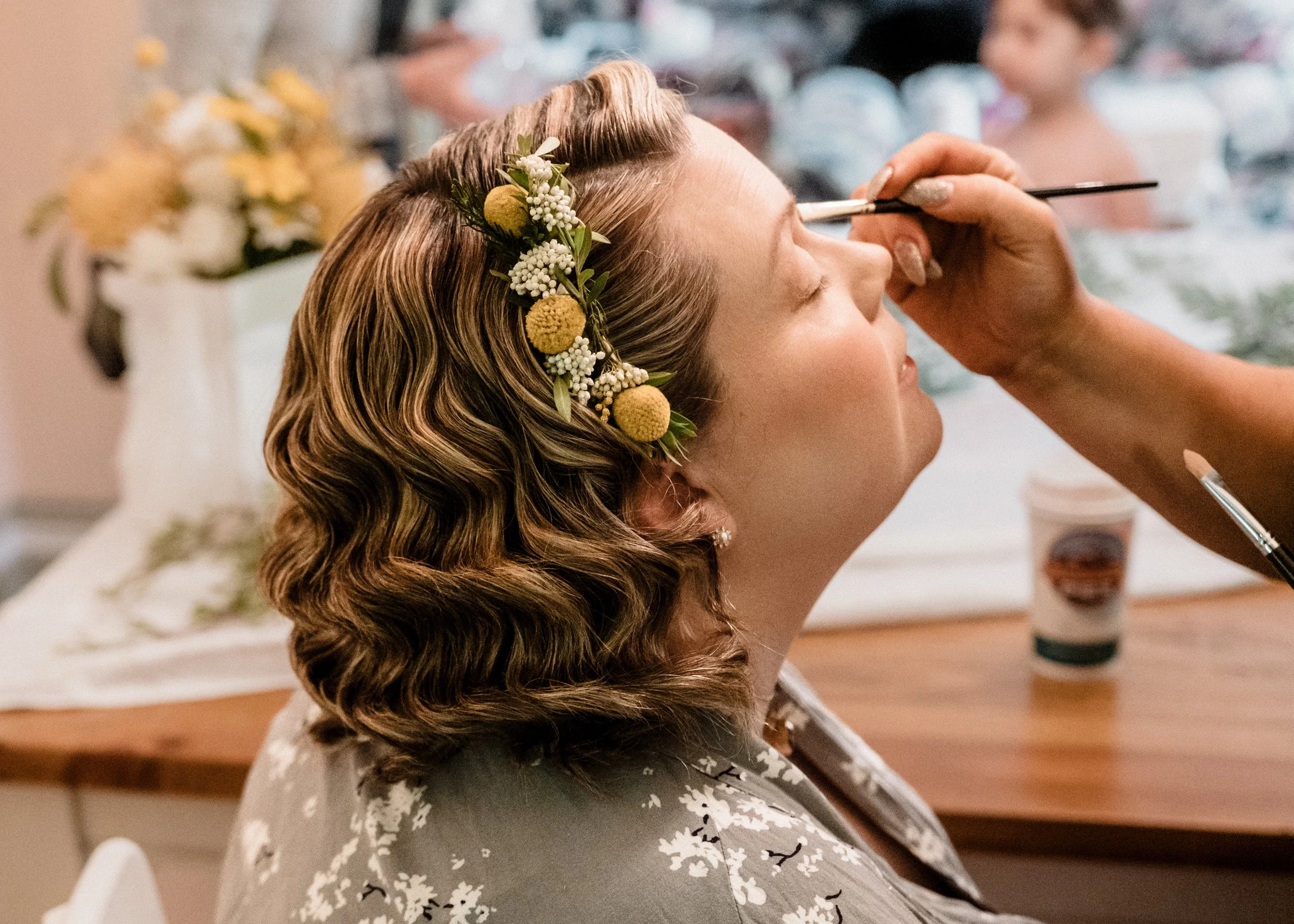 A bride gets her makeup done before her intimate Blue Mountains elopement — soft light, delicate florals, and natural beauty.
