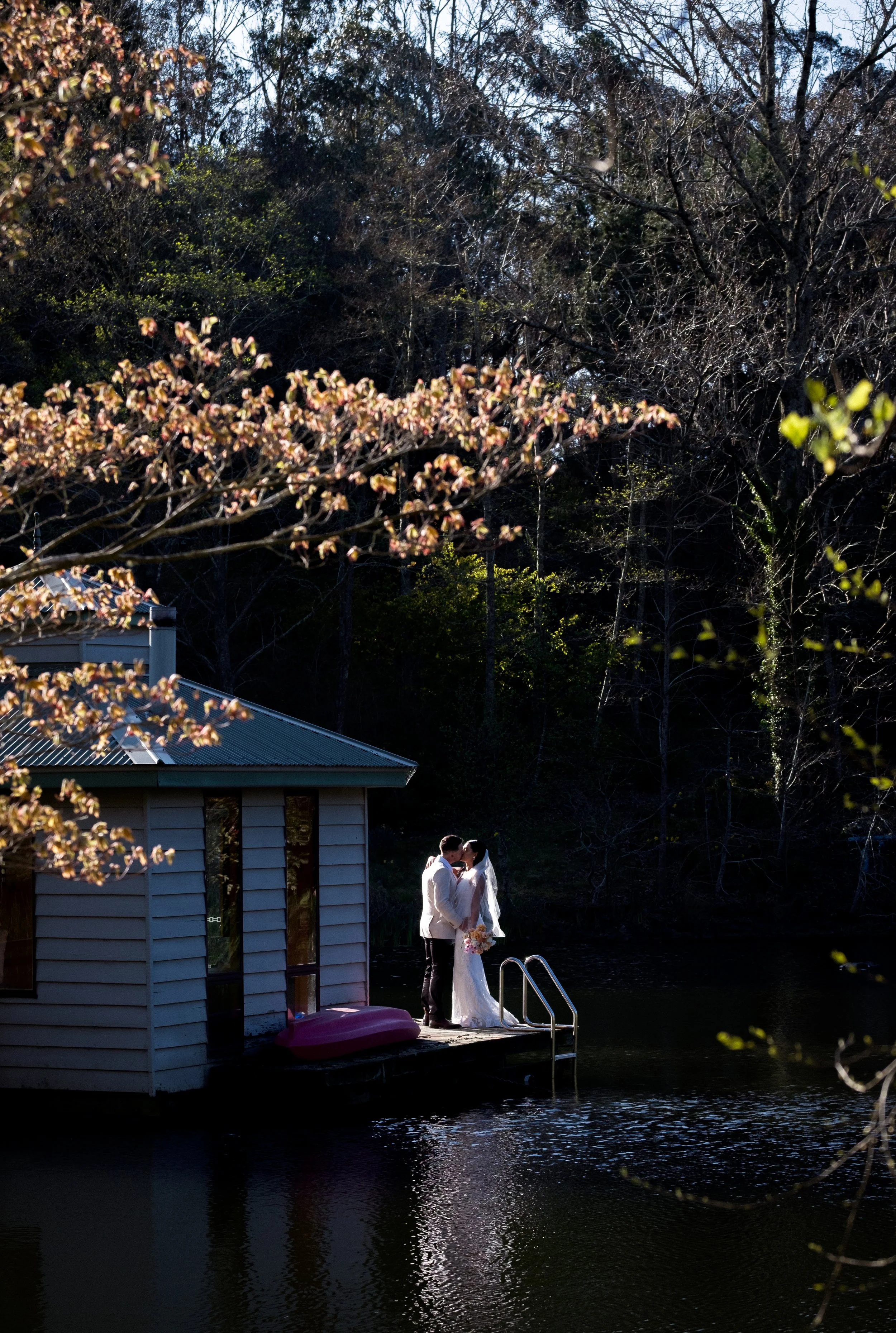 A bride and groom share their first kiss beside a quiet lake at sunset — a beautiful, romantic Blue Mountains elopement setting.