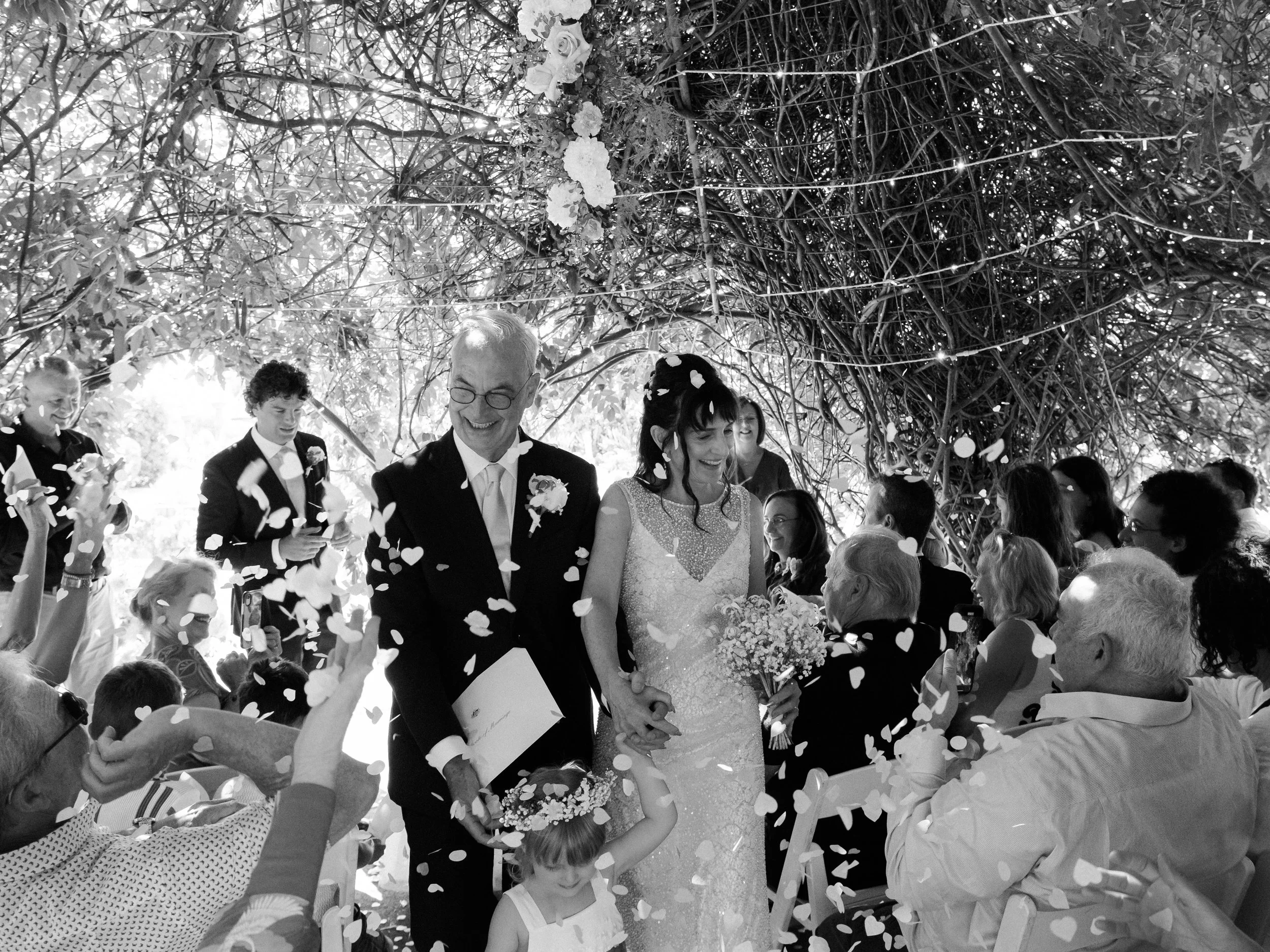 A black-and-white photo captures the joy of a Blue Mountains elopement ceremony as the newlyweds walk through a shower of confetti.