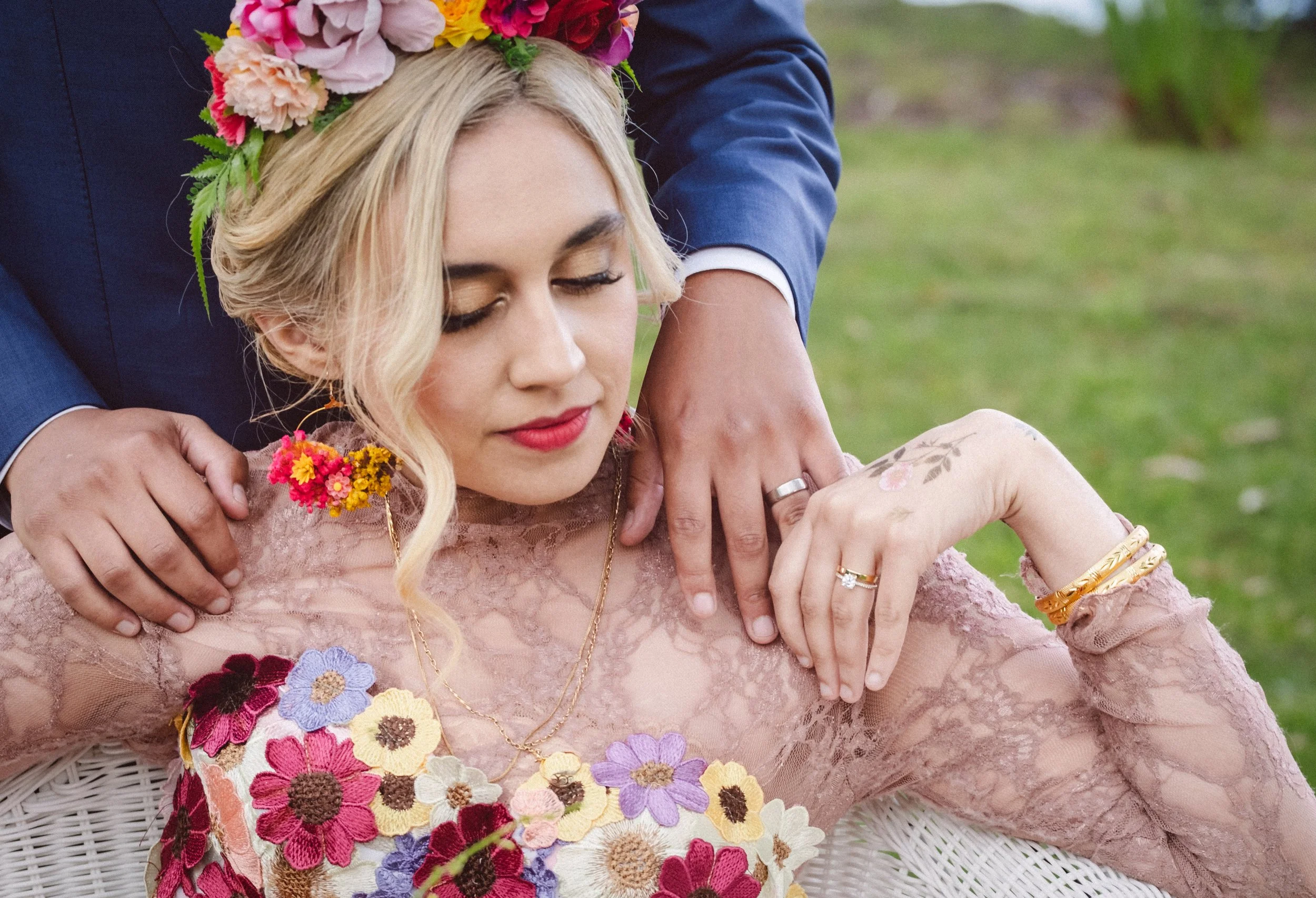 Bride wearing a floral crown and embroidered gown during an intimate Blue Mountains elopement, groom in blue suit gently touching her shoulder in a romantic outdoor moment.