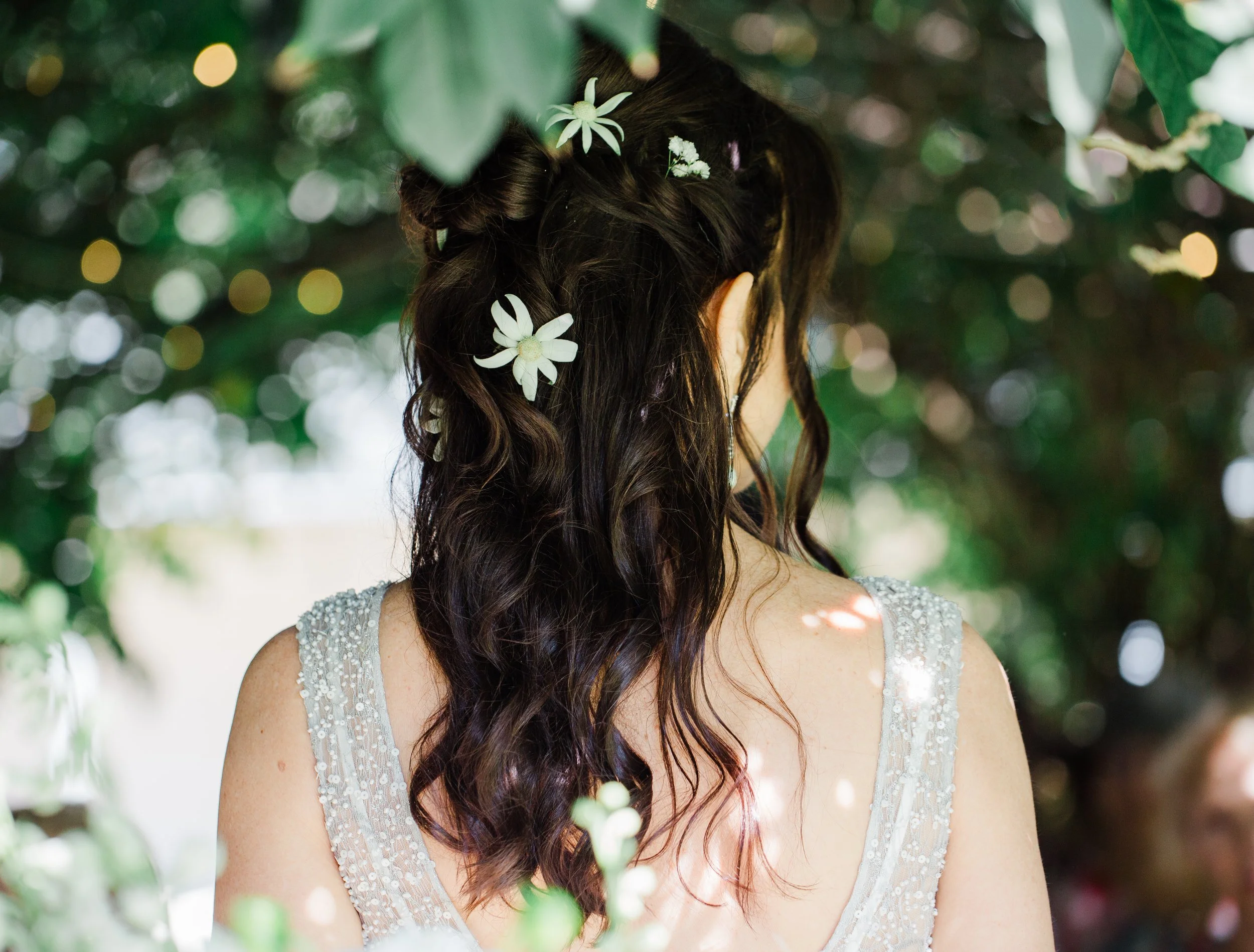 Back view of a bride with floral hair accessories, surrounded by soft greenery — a romantic detail from a Blue Mountains elopement.