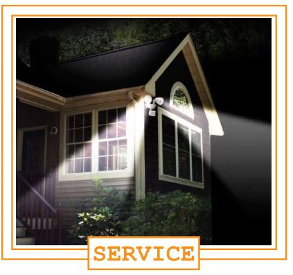 Nighttime exterior house with porch lights on, illuminated window, and a sign that says 'SERVICE'.