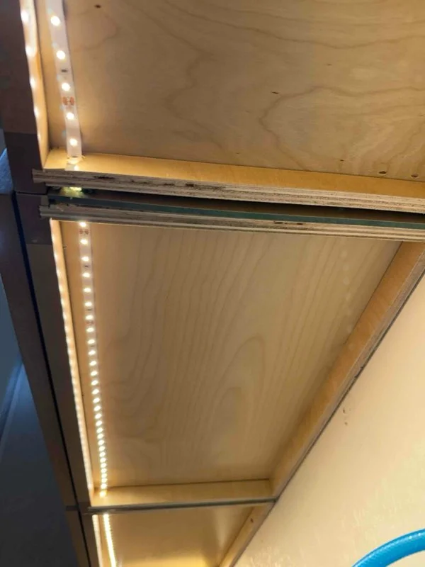 Close-up of an empty wooden shelf with LED strip lighting on the edge.