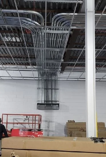 Multiple electrical conduit pipes running from ceiling to wall in an industrial or commercial space.