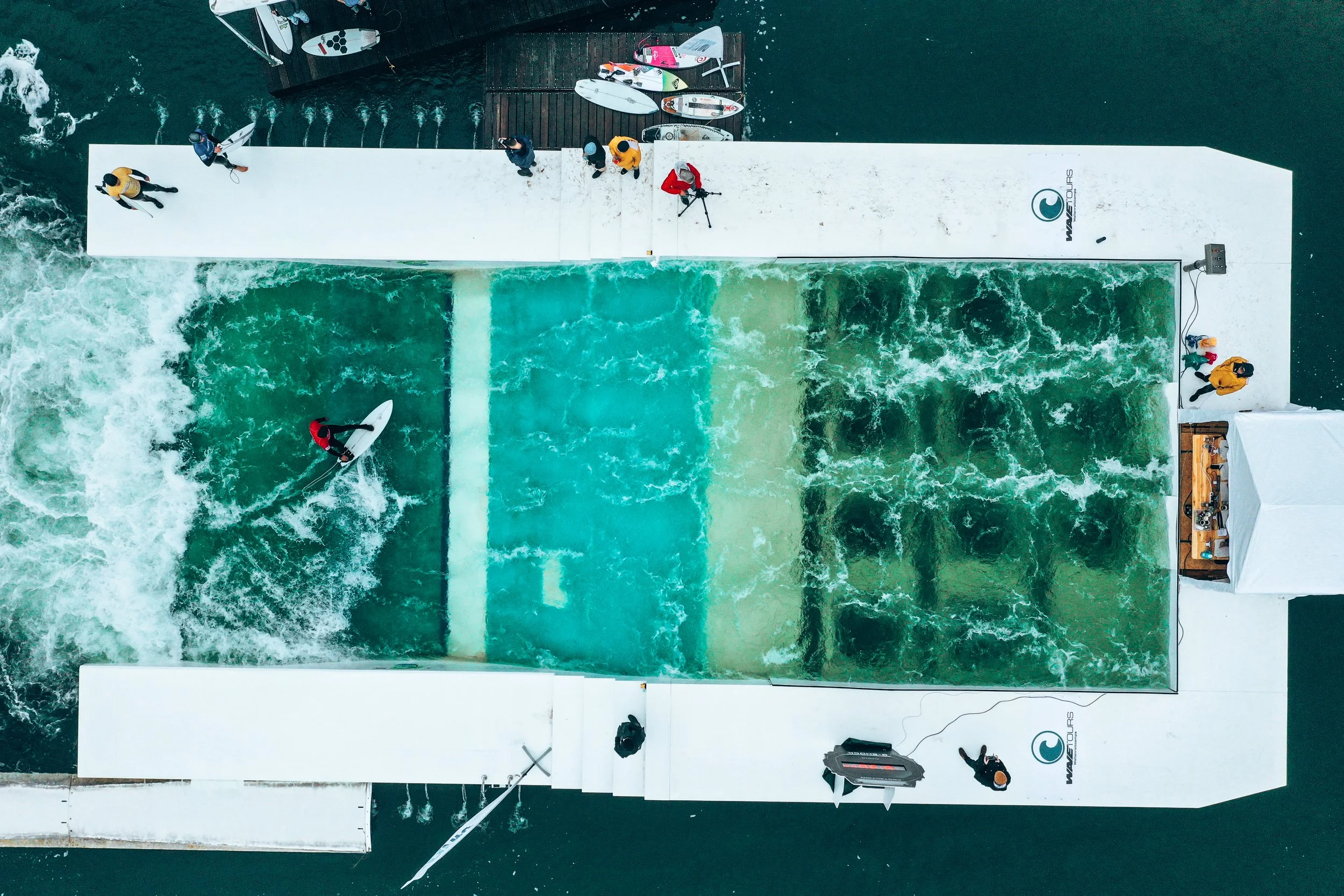 Ein Wasserrutschbahn für Wassersportarten mit Surfern, Leuten auf dem Ufer und Wasser für Wakeboarding.