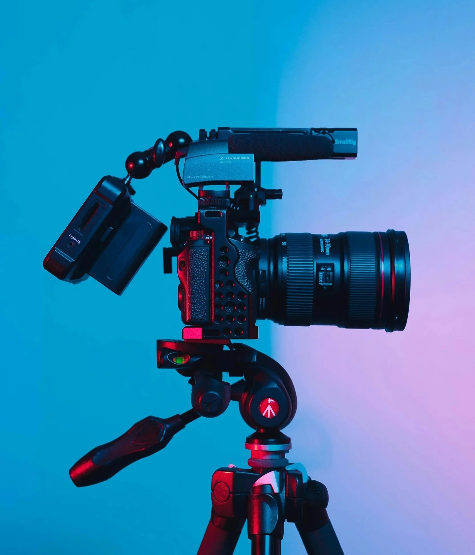 Camera on a tripod with mounted microphone against a blue and purple gradient background.