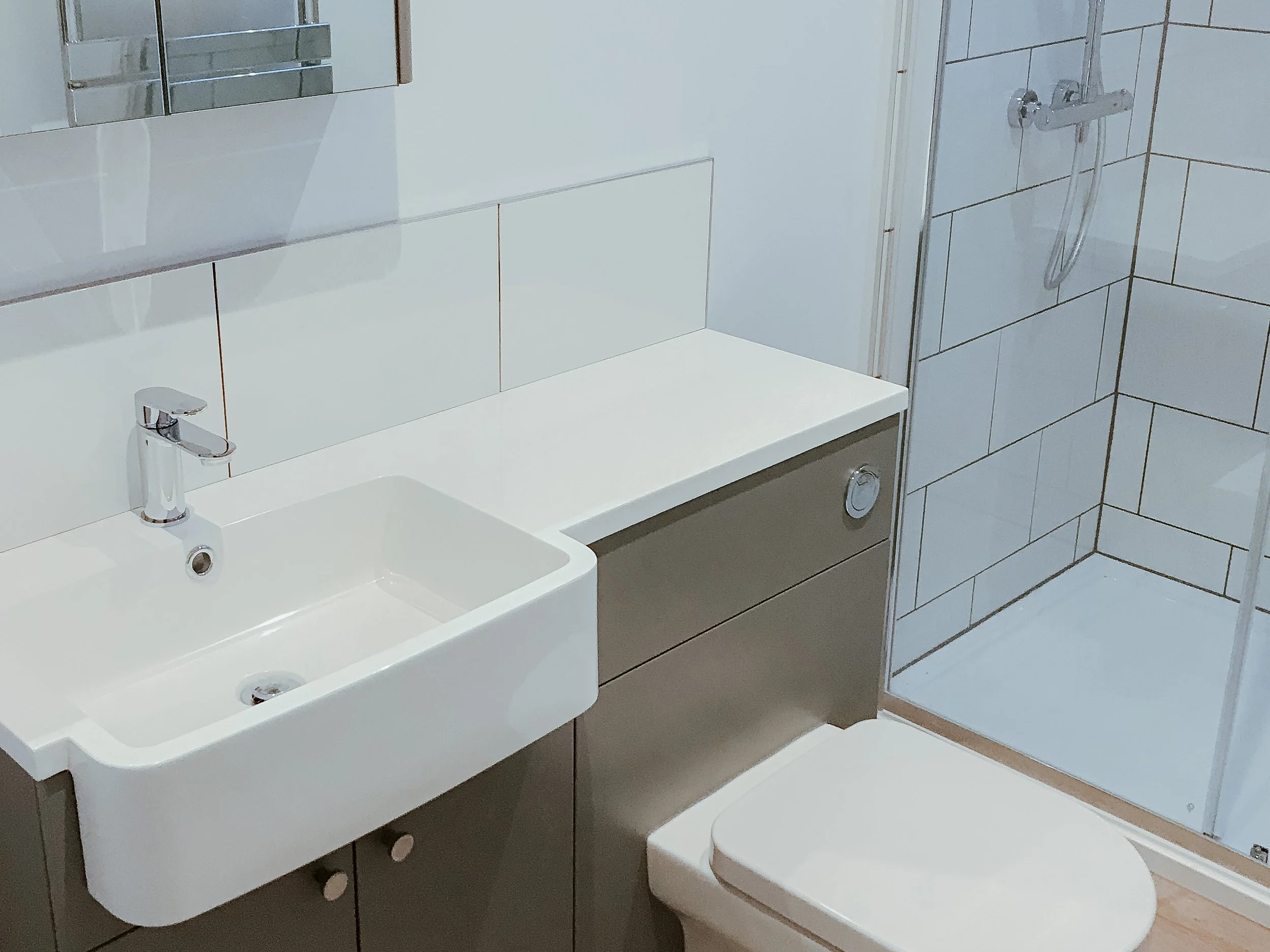 Small bathroom with a white sink, a mirror, a gray cabinet, a toilet, and a shower enclosed with glass doors.