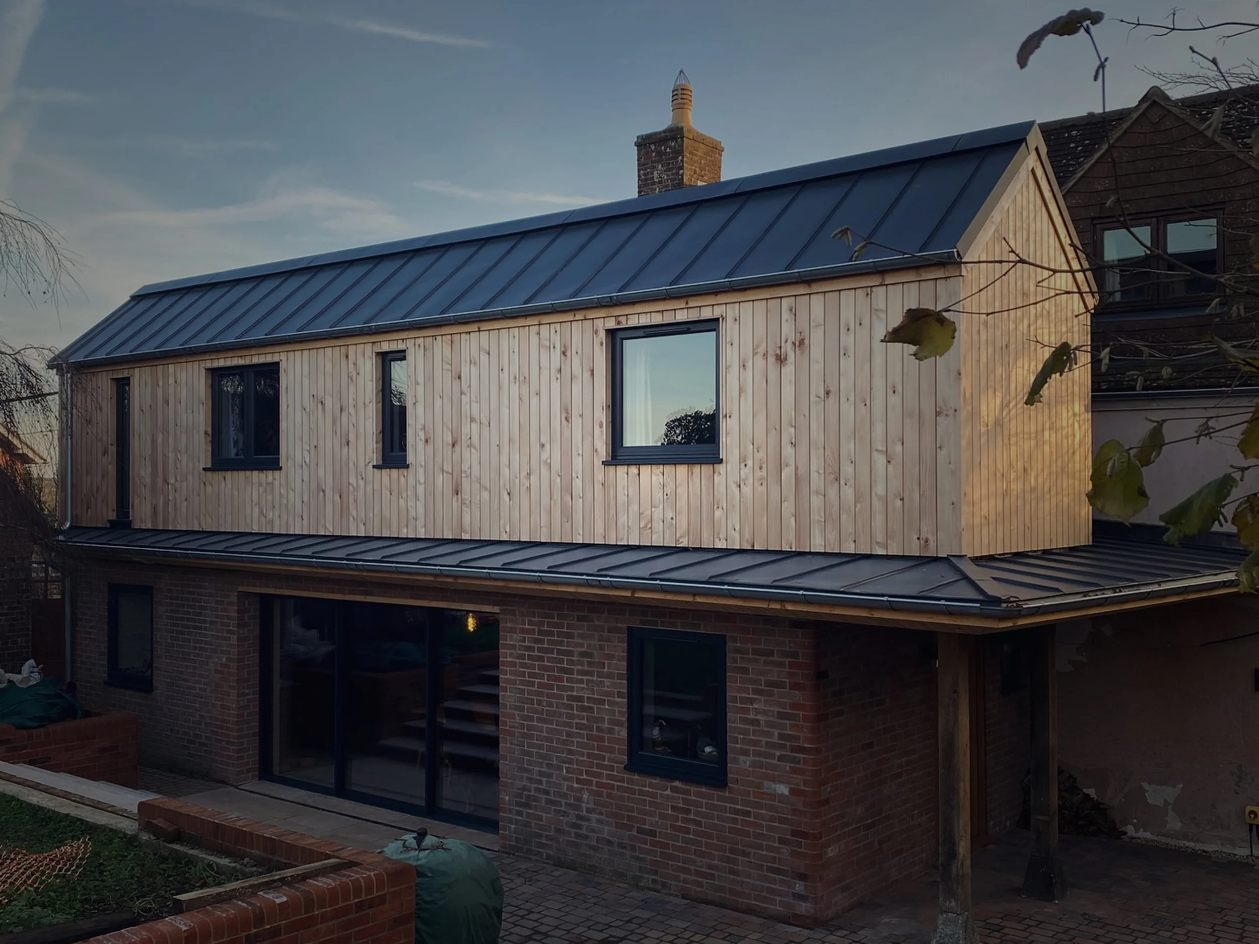 A two-story house with a brick lower level and a wooden upper level, large home extension.