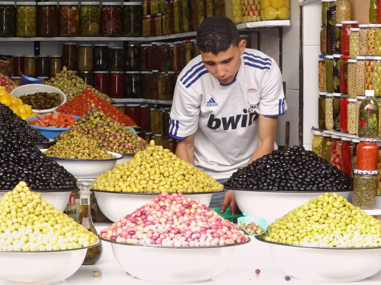 11 - The Olive Seller.

Visual emphasis: individual identity, occupation and social setting.

"A person is encountered through the work they do and the social setting in which they do it. The photograph considers how occupation shapes public identity