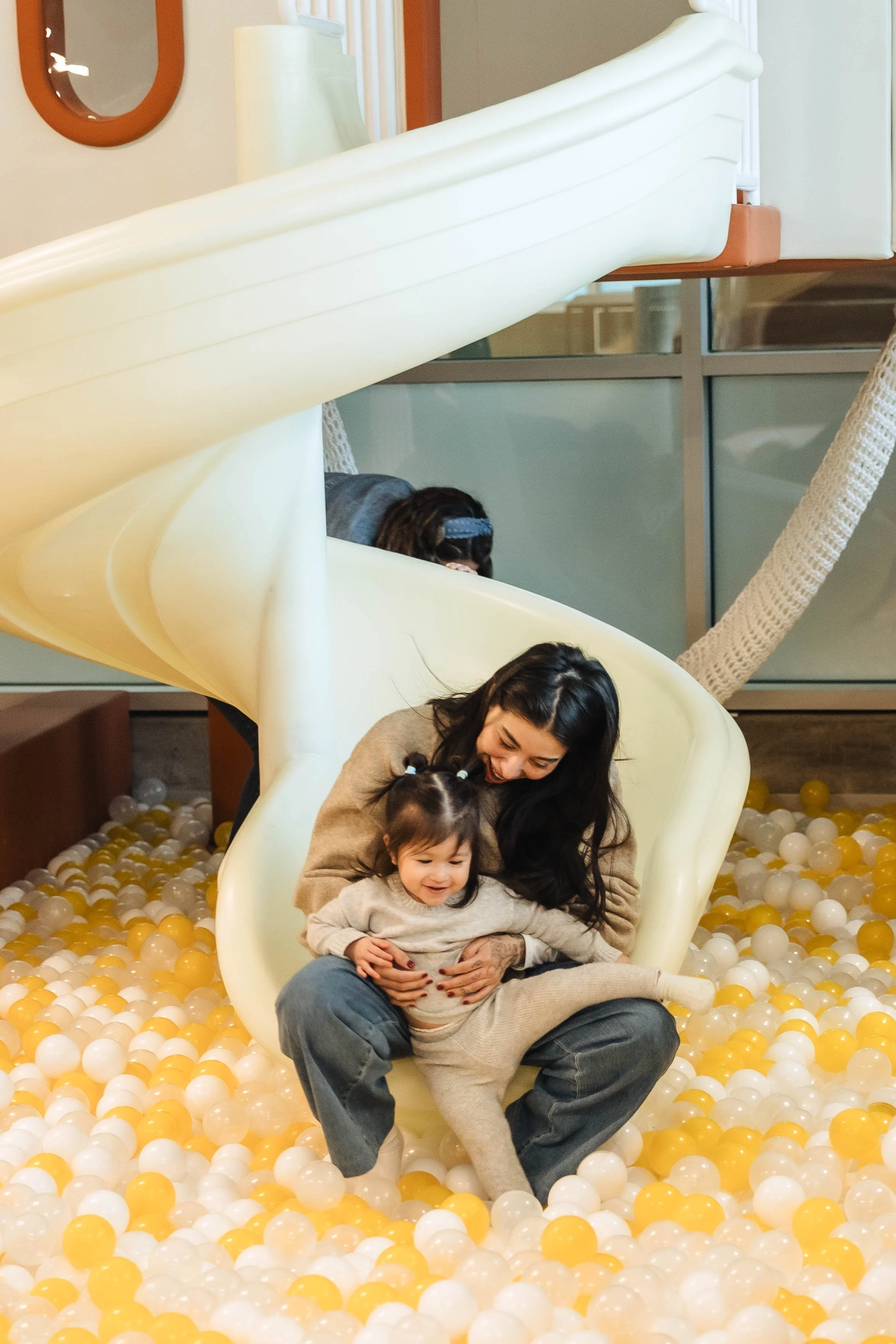 A young boy playing with sand at a table, with toy cars and drawings on paper next to him.
