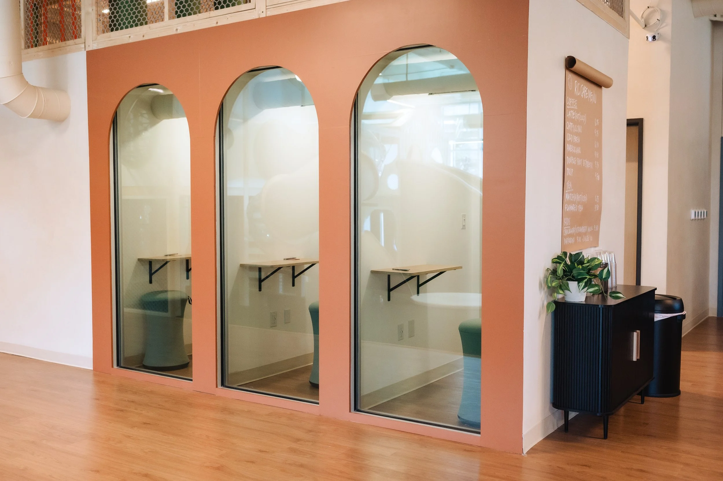 A person working on a laptop at a wooden table, wearing a smartwatch on their left wrist and multiple rings on their fingers.