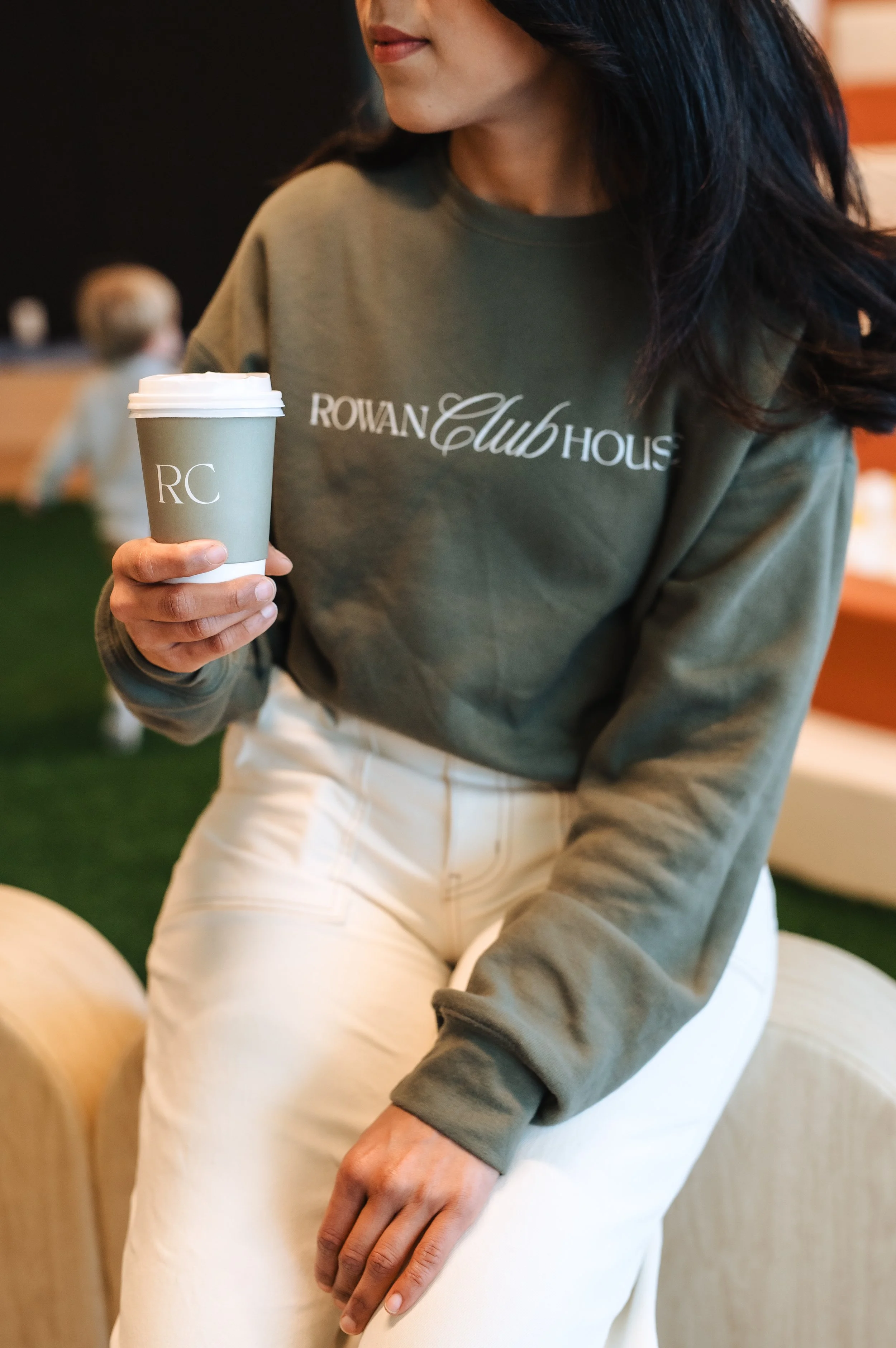 A white cup filled with black coffee on a white saucer, casting a shadow on a white surface with dark background lighting.