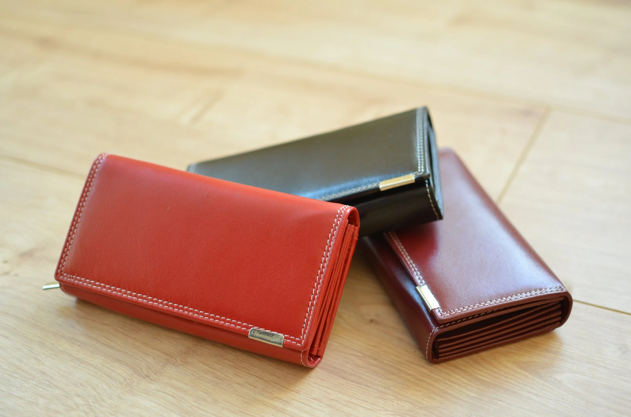 Drei Leder-Geldbörsen in Rot, Braun und Schwarz – hochwertige Produkte von Lederwaren Boche im Kommissionssystem für stationäre Händler.