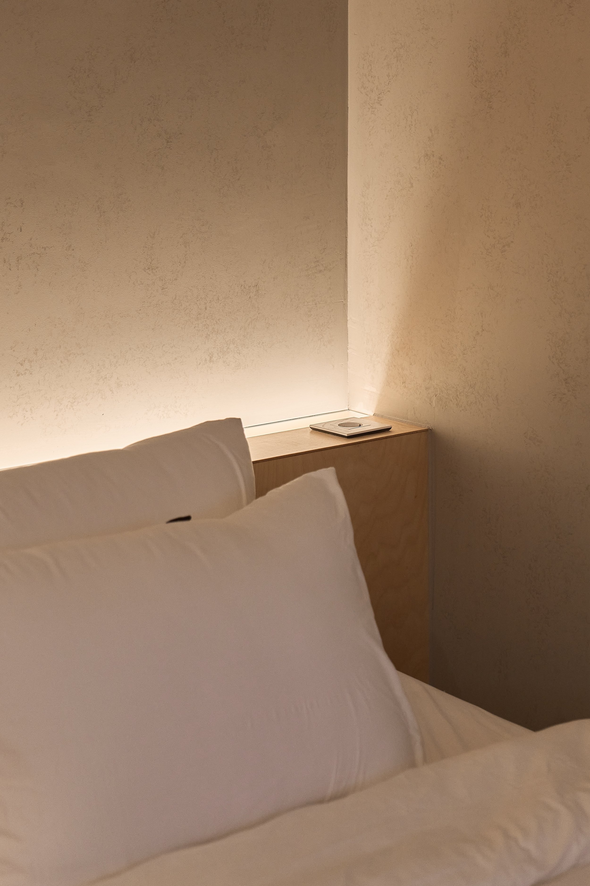 willow leaf Gangnam Room 201 bedroom with soft lighting, minimalist wood bedside shelf, and crisp white bedding designed for a calm and restful recovery stay.