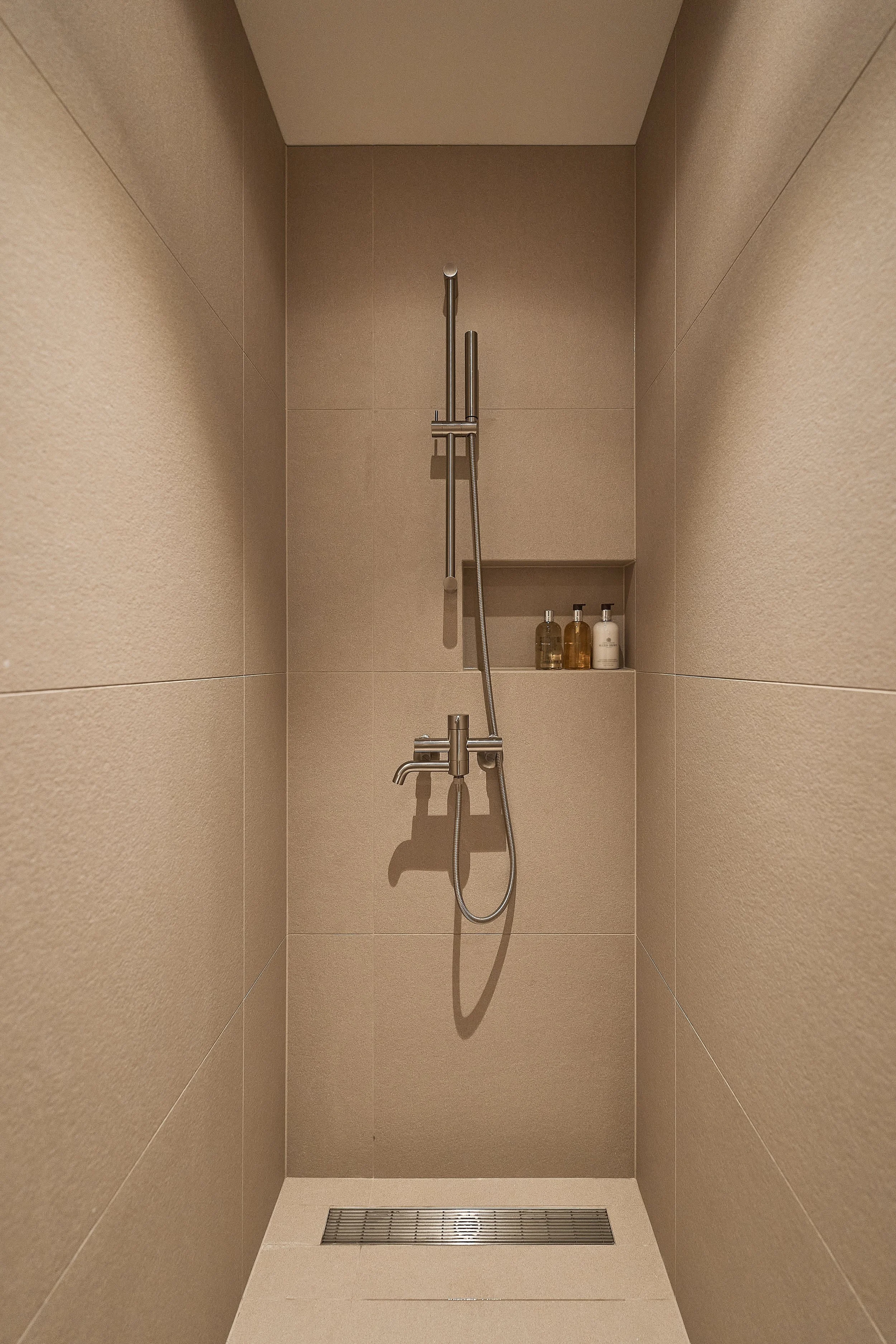 Minimalist walk-in shower at willow leaf Gangnam featuring modern brushed metal fixtures and premium Molton Brown amenities, designed for a calm and comfortable recovery stay.
