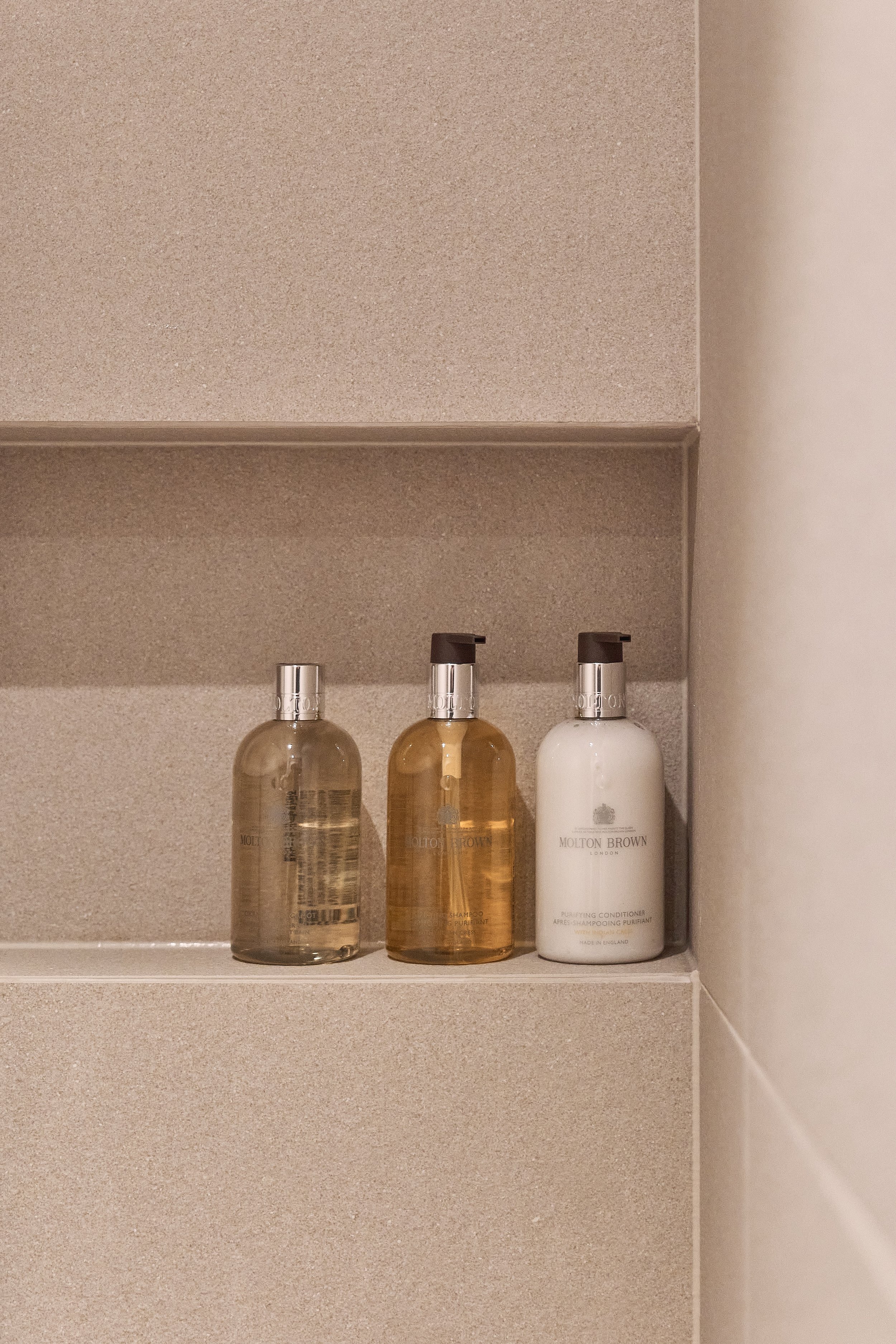 Molton Brown shampoo, body wash, and conditioner displayed in the minimalist bathroom of willow leaf Gangnam, offering premium amenities for a comfortable recovery stay.