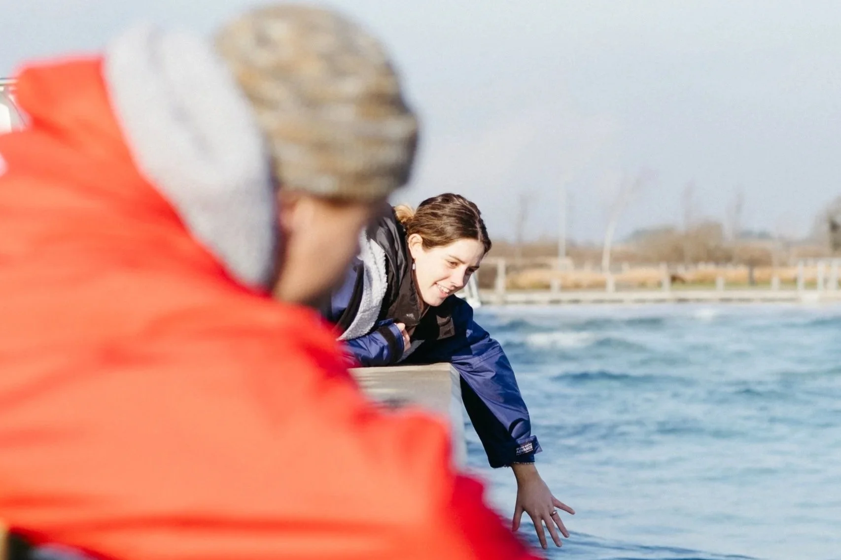 A woman in a yellow helmet smiling and talking with two other helmeted individuals in a workshop or sports store.