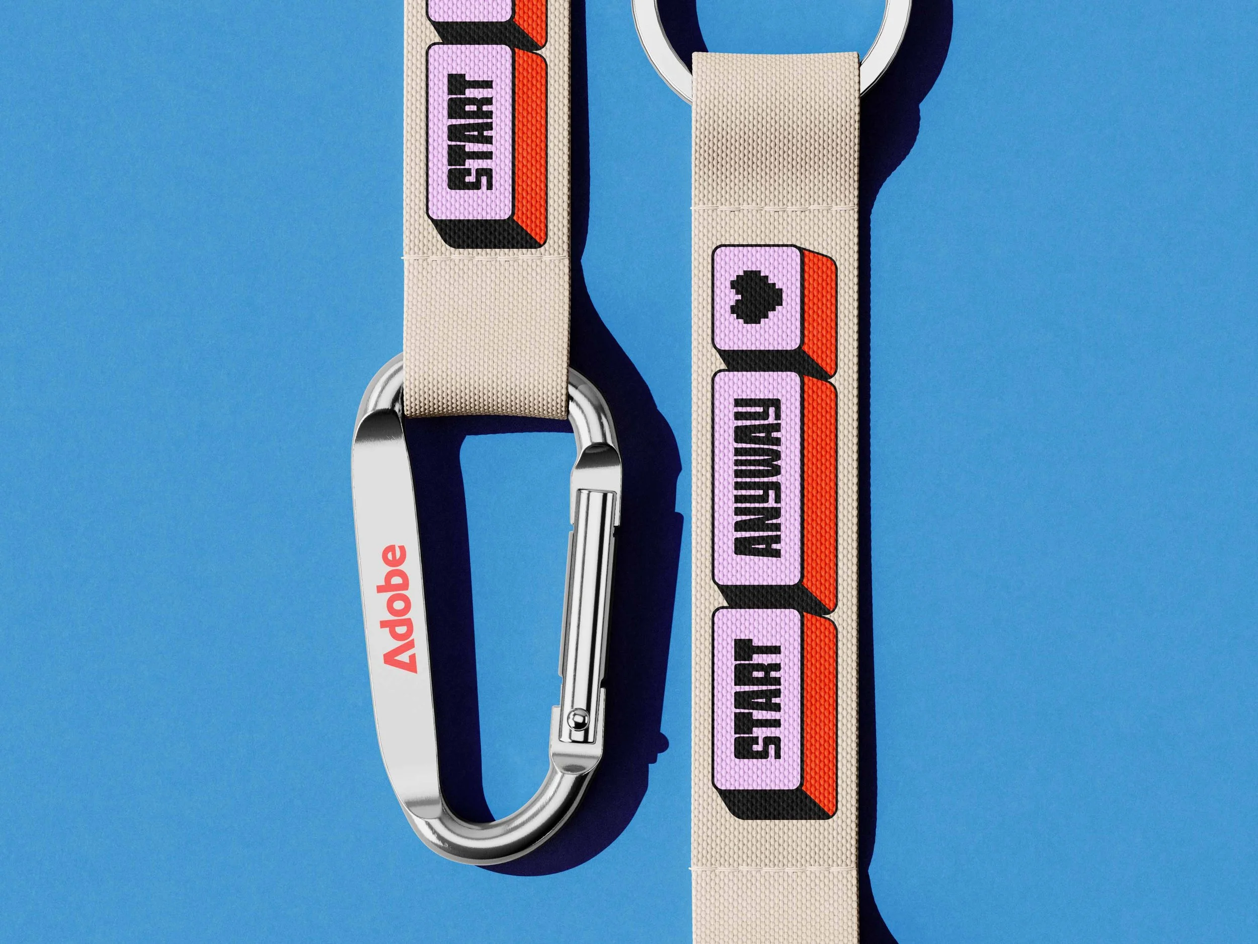 A woven fabric strap with a metal hook and a label reading "ADOBE" attached to a circular metal ring, set against a blue background.