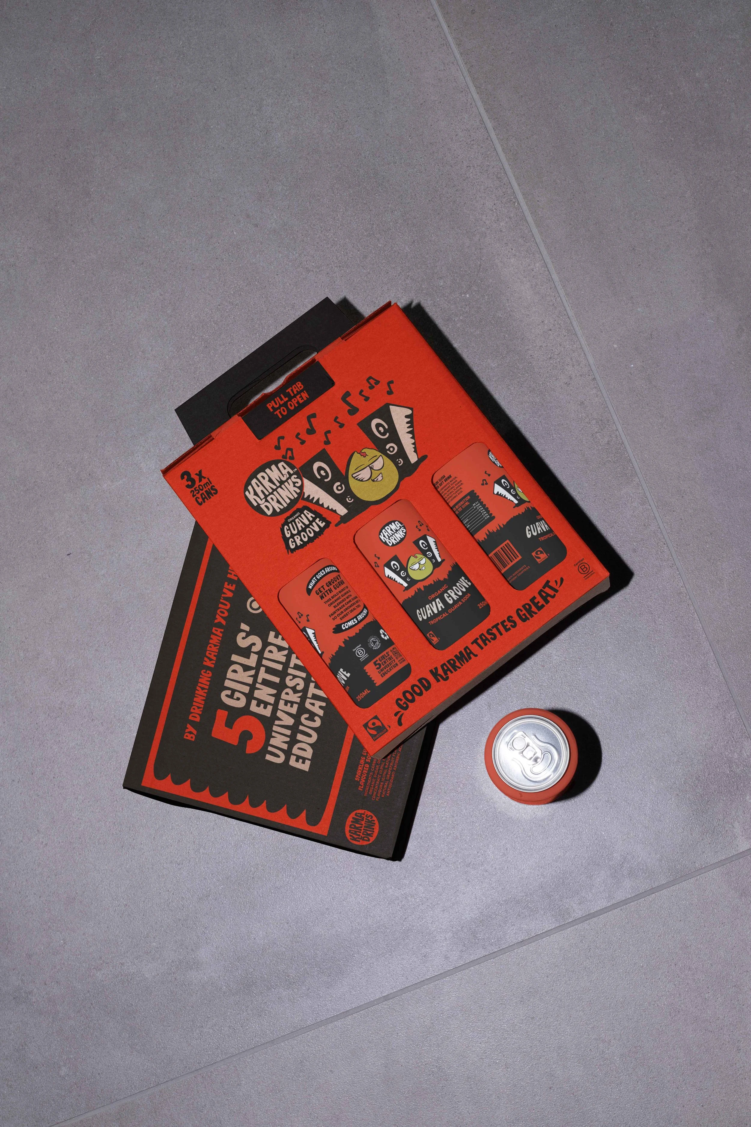 A flat lay of a ramen noodle drink kit box, a soda can, and a box of ramen noodle packs on a gray tiled floor.