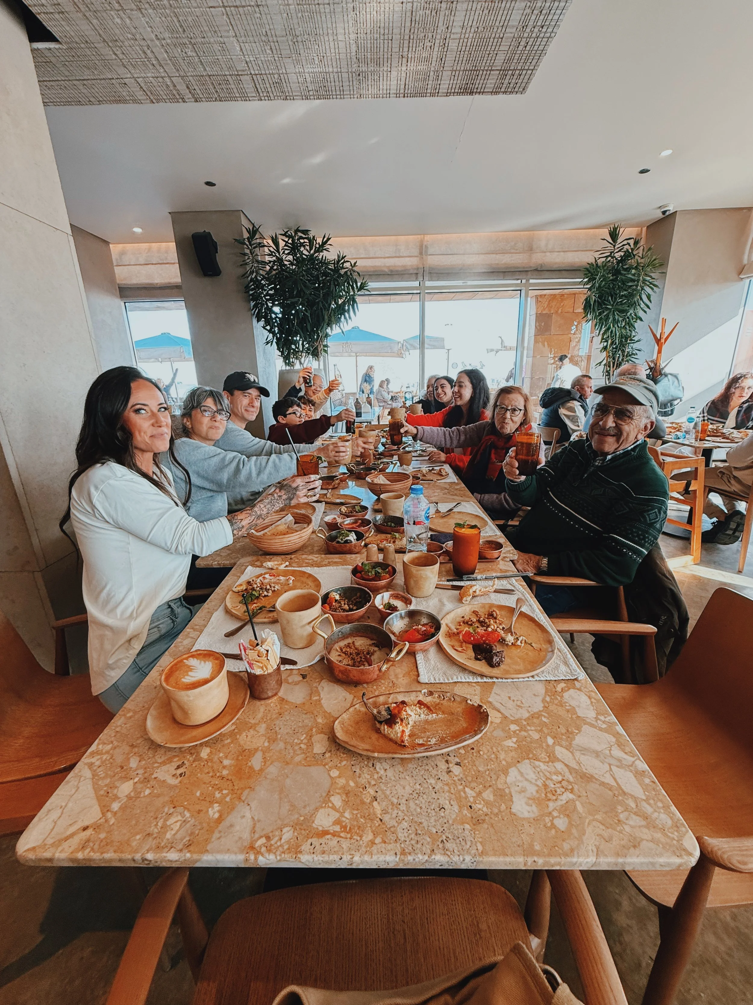 Jennifer sharing a long Egyptian dinner with a family of guests, everyone raising their glasses in a toast around a table full of shared dishes