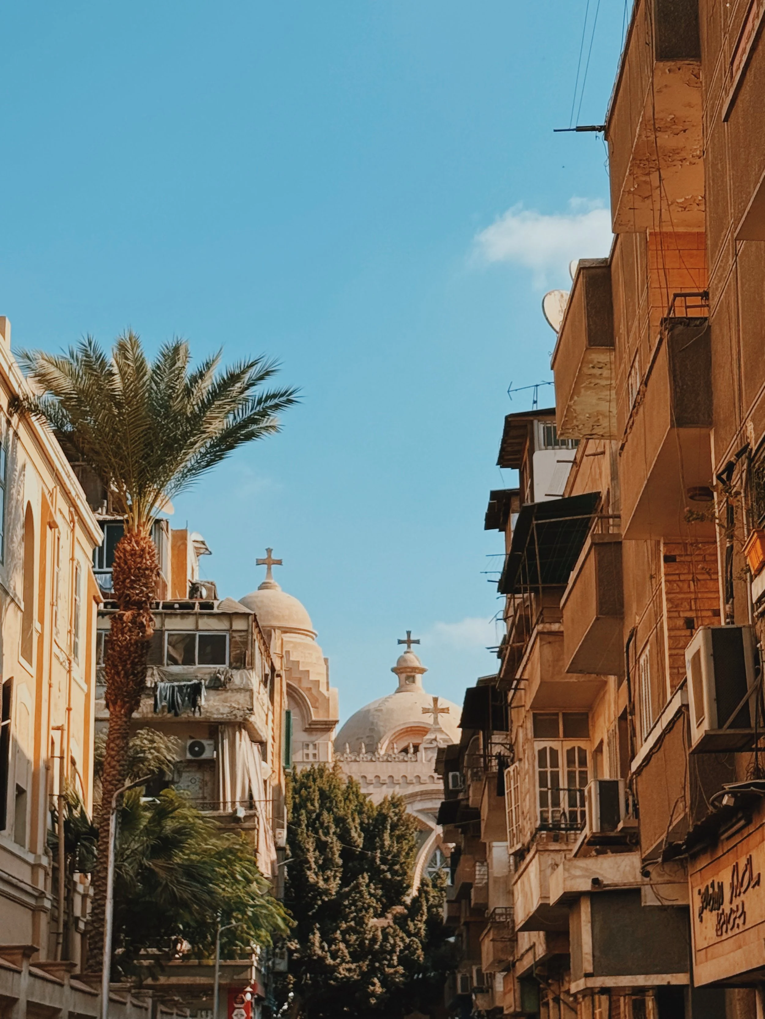 The domes and crosses of a Coptic church rising between old apartment buildings in Cairo.