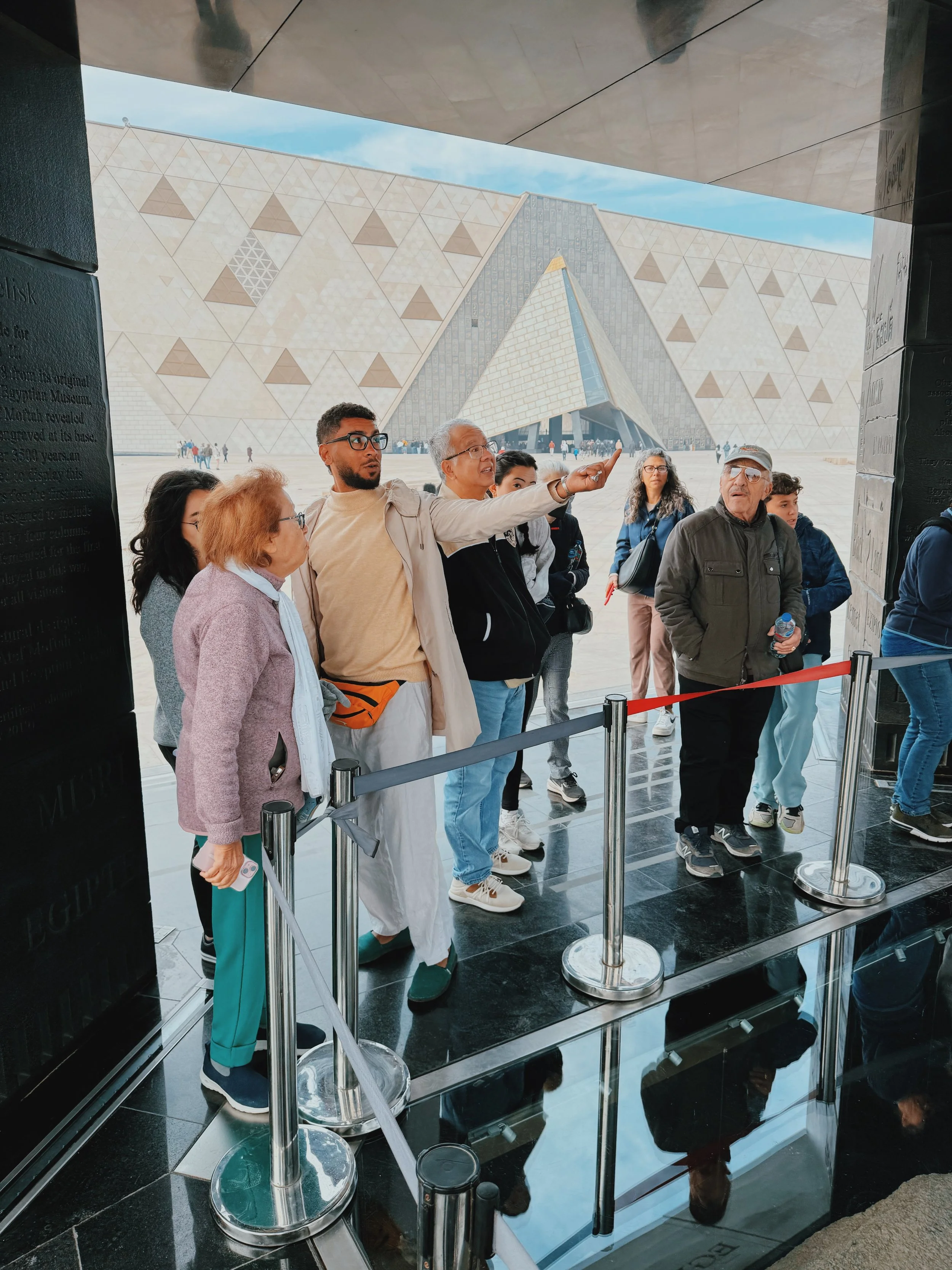 Egyptologist Mostafa pointing out the hanging obelisk to guests outside the Grand Egyptian Museum.