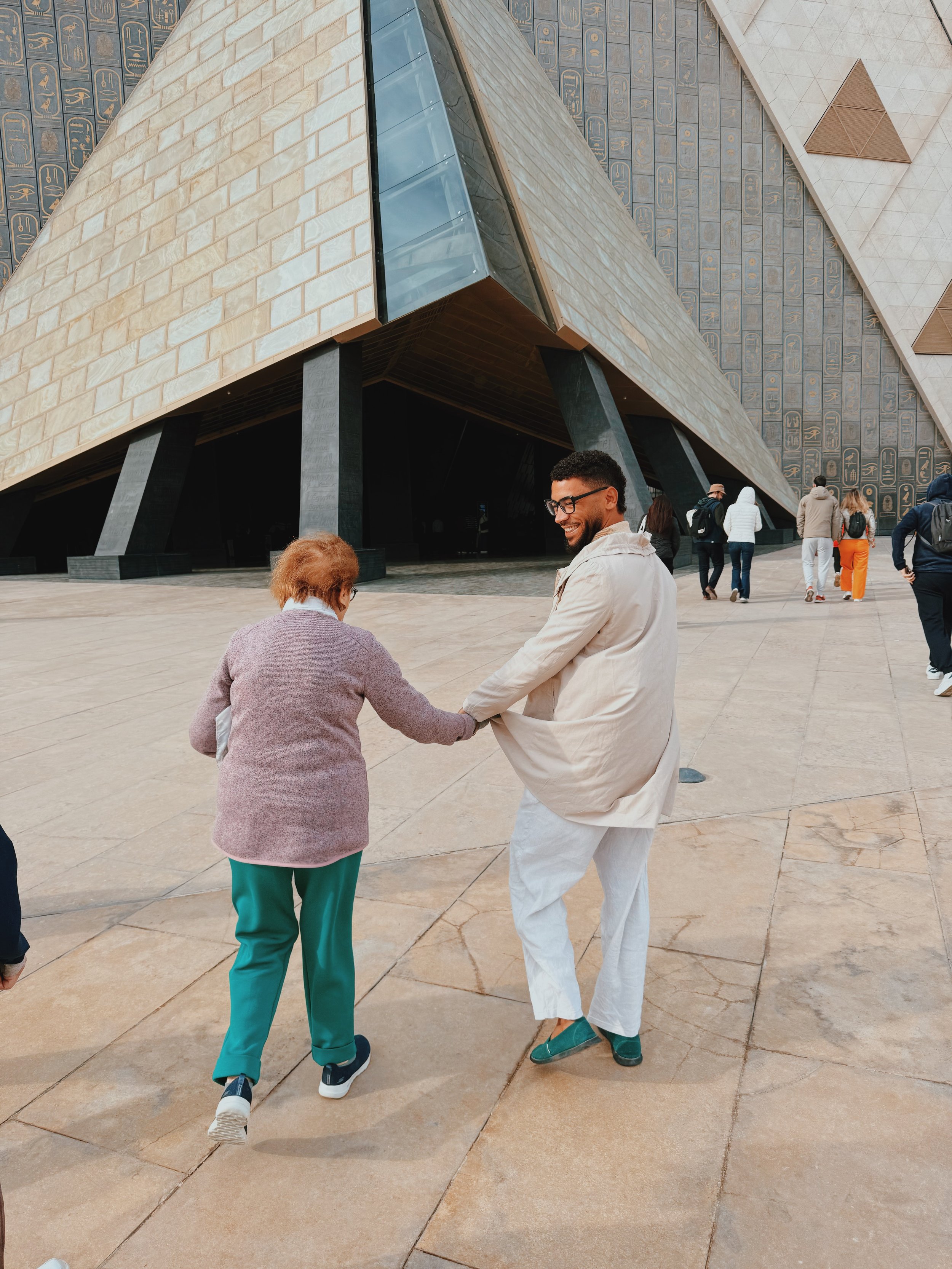Mostafa of Takemet Tours smiling as he leads a guest by the hand into the Grand Egyptian Museum