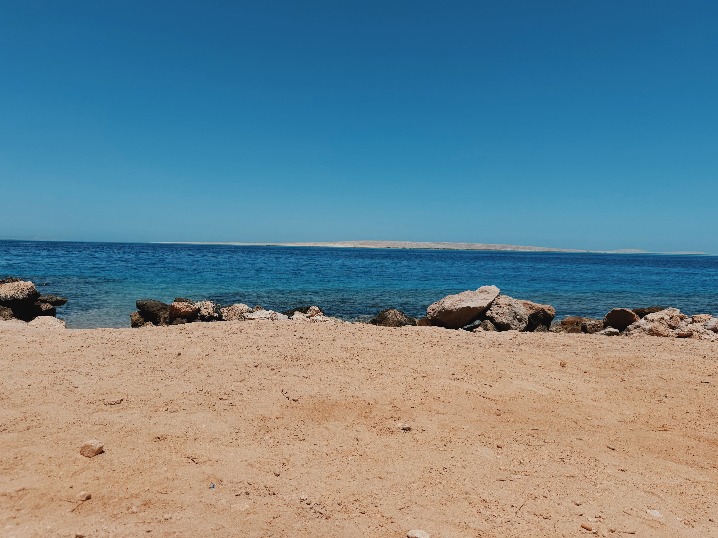 A quiet sandy beach and rocky shoreline on the turquoise Red Sea at Hurghada.