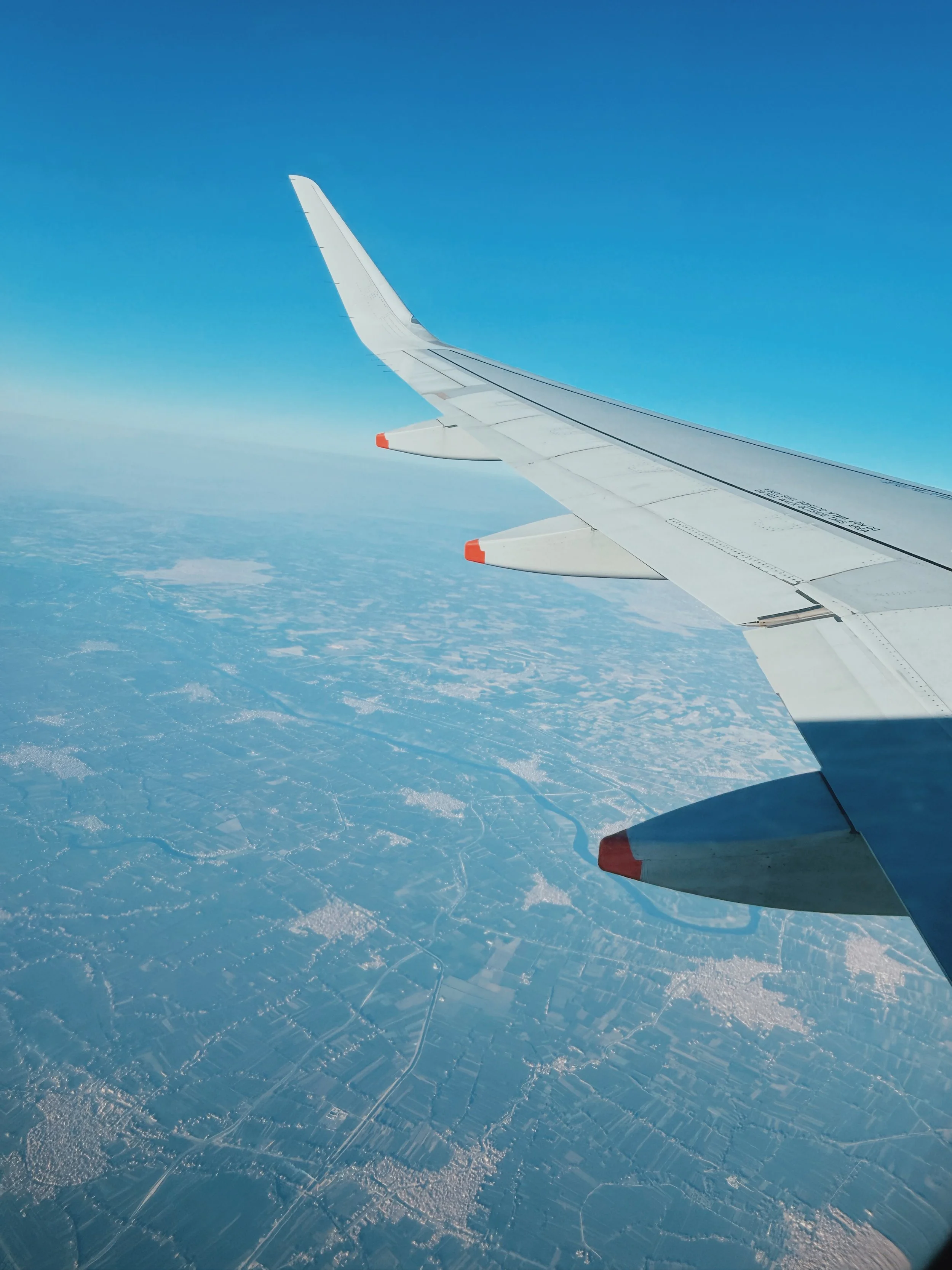 View from an airplane window of the wing over green farmland and a winding Nile river.
