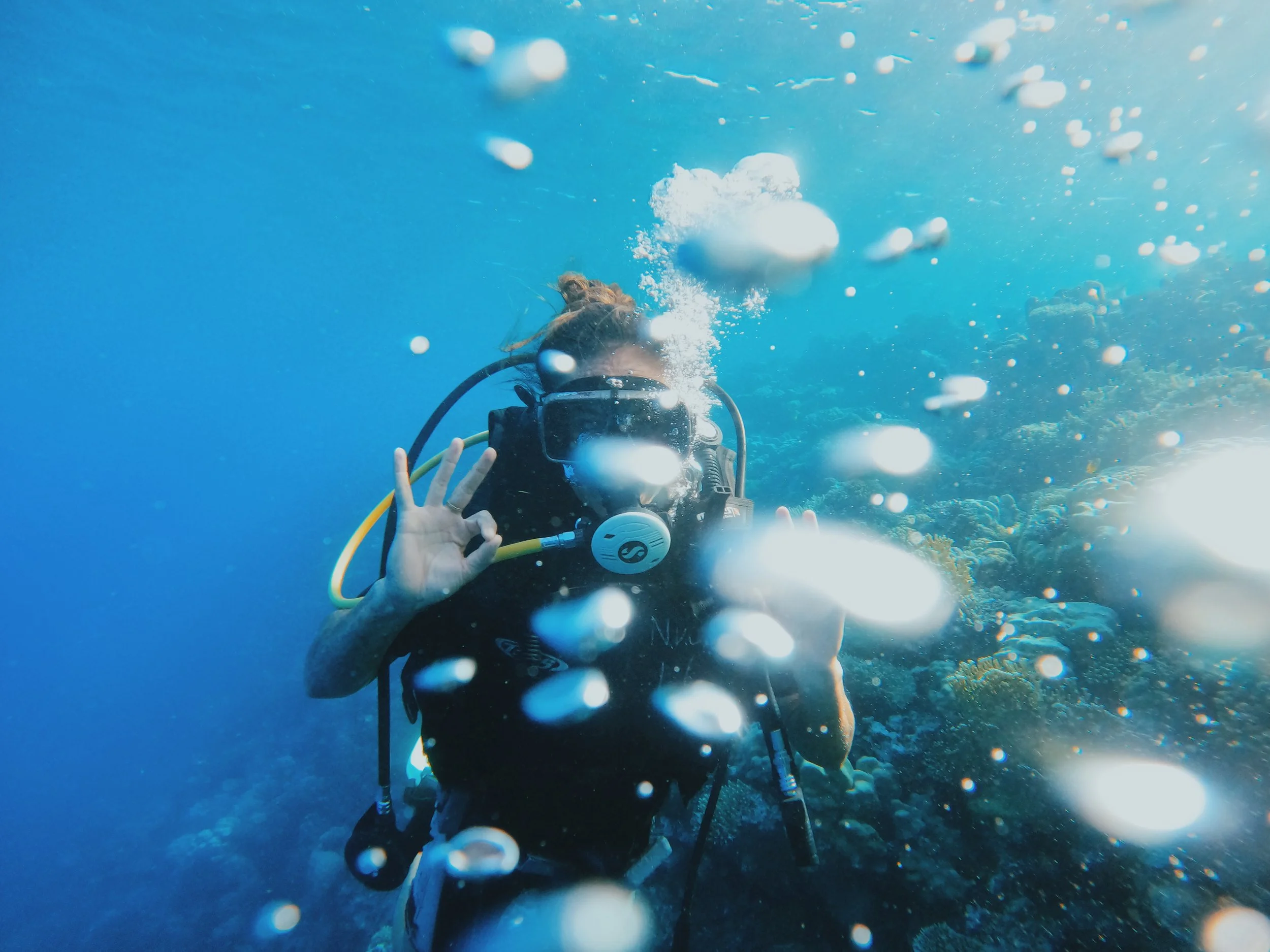 A Takemet guest giving the OK sign while scuba diving over a coral reef in the Red Sea at Dahab.