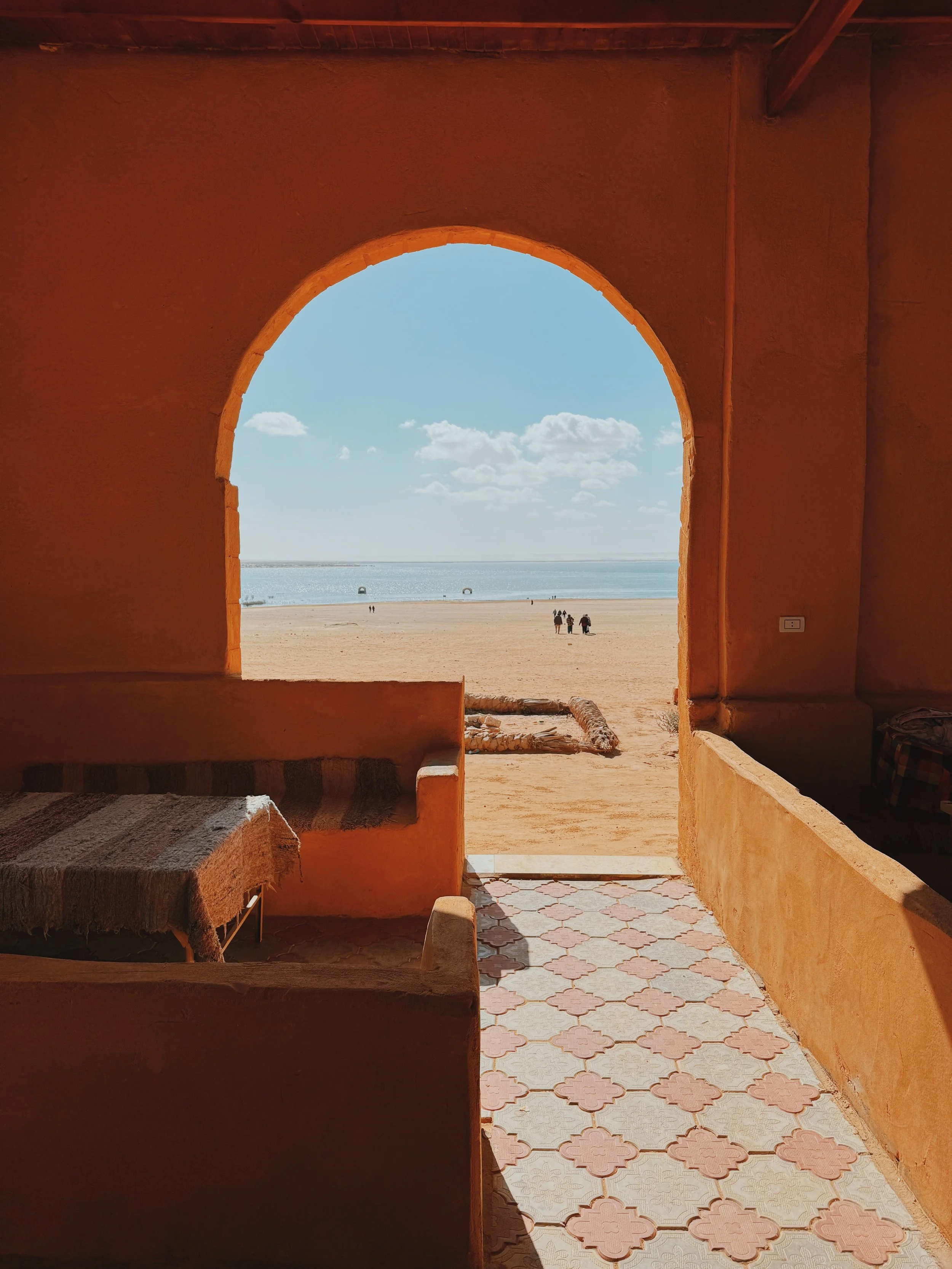 A view through an arched doorway to the sandy shore of the Wadi El Rayan lakes in Faiyum.
